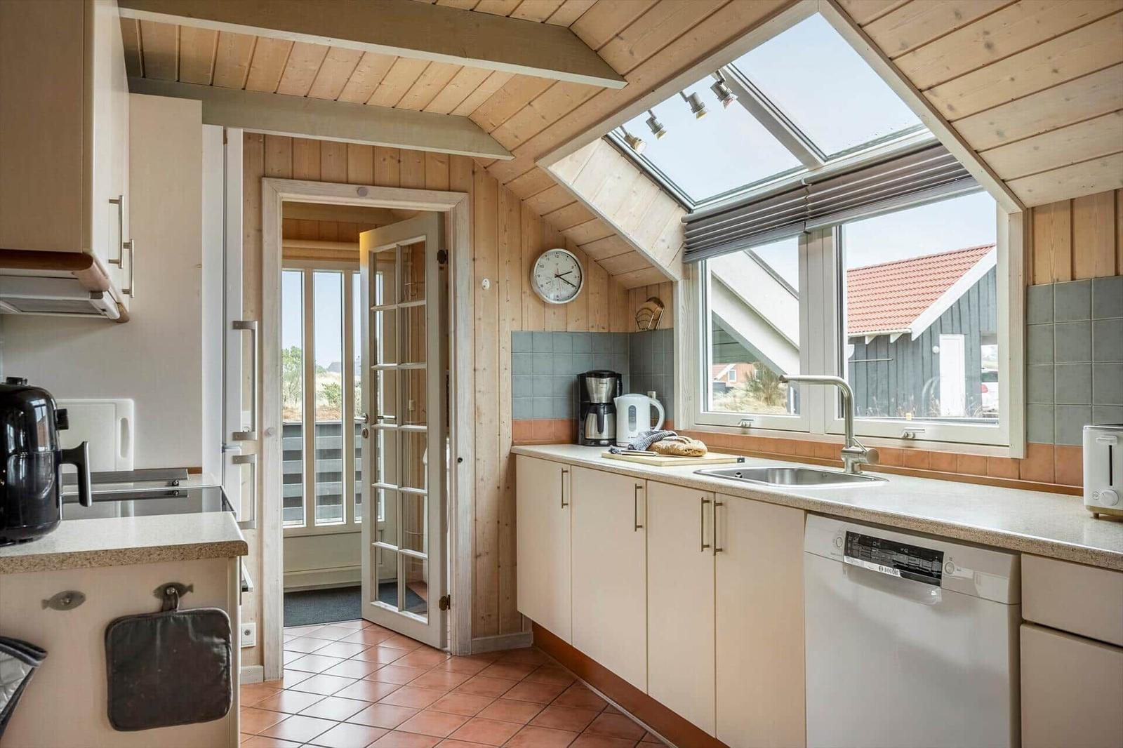 Küche mit Holzwand, Dachfenster und Blick auf Terrasse.