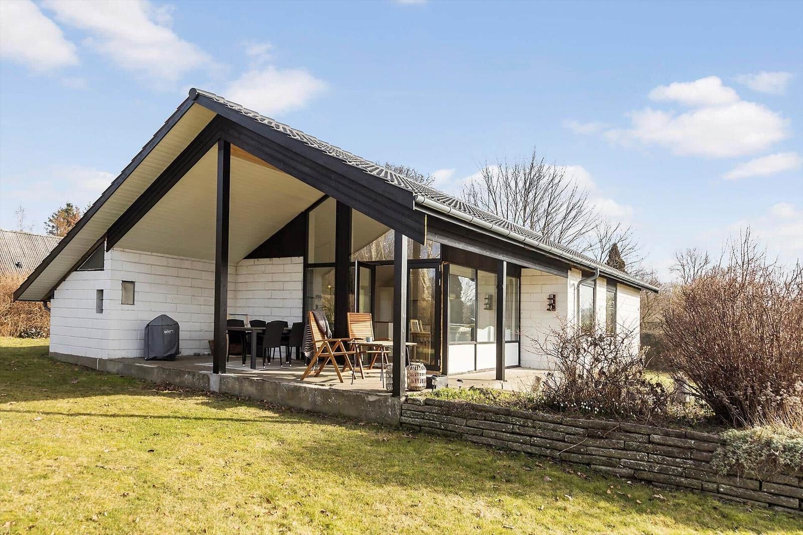 Moderne Villa mit Terrasse, Garten und Sitzgelegenheiten. Glasfronten und Holzgestell.