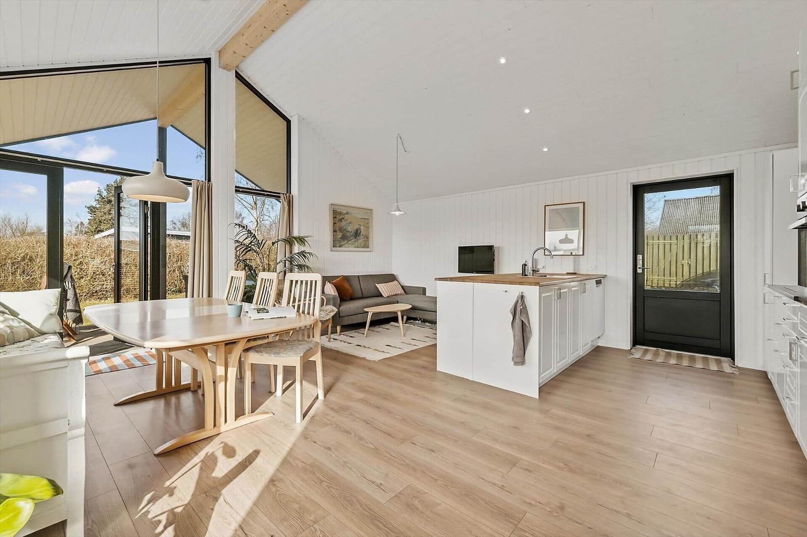 Moderne offene Küche mit Essbereich und Wohnzimmer. Holzfußboden und große Fenster.