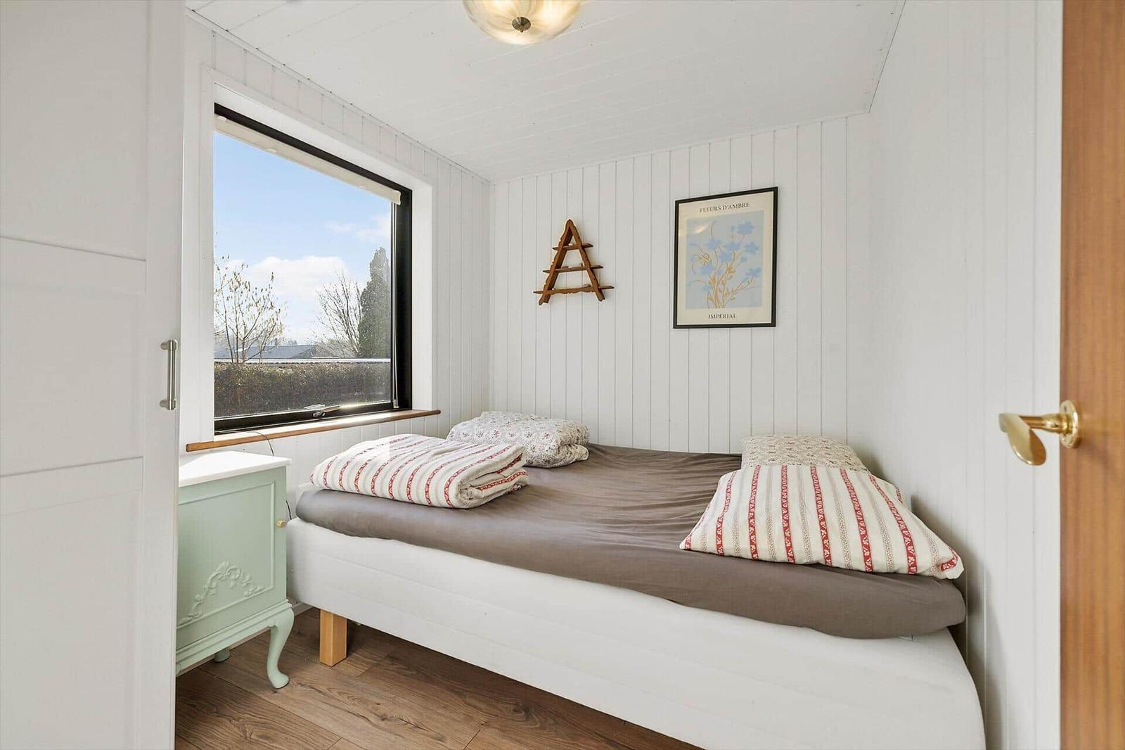 Schlafzimmer mit Bett, Fenster und Nachttisch.