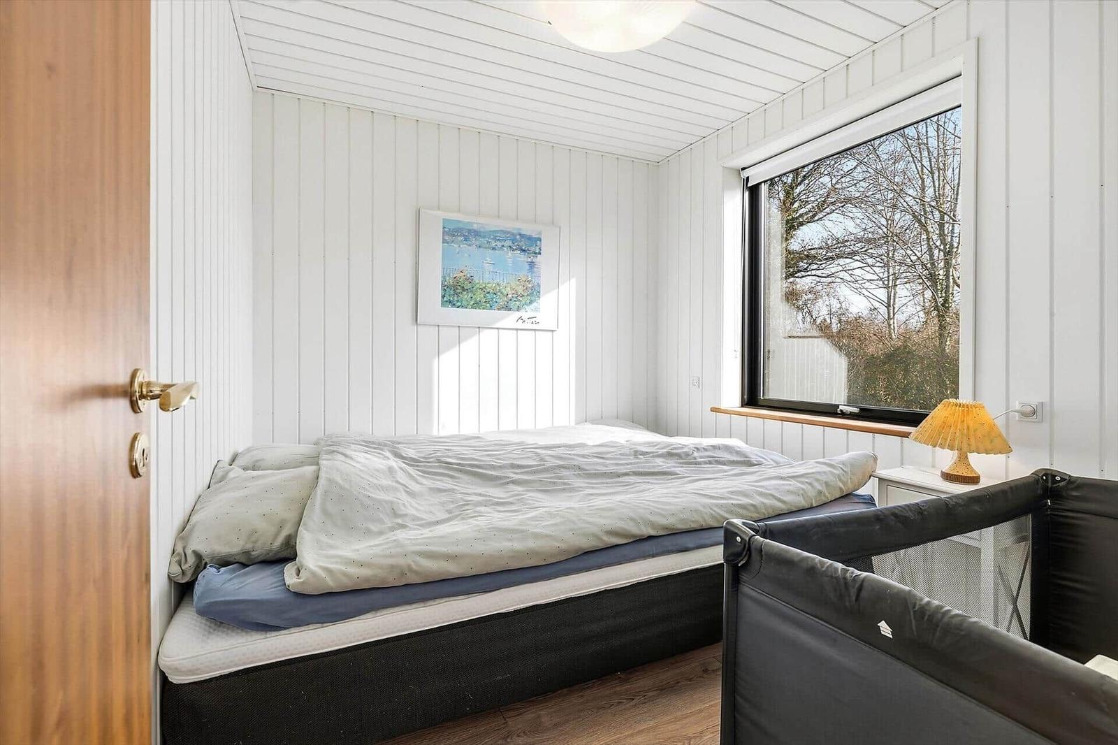 Schlafzimmer mit Bett, Fenster und Kinderbett.