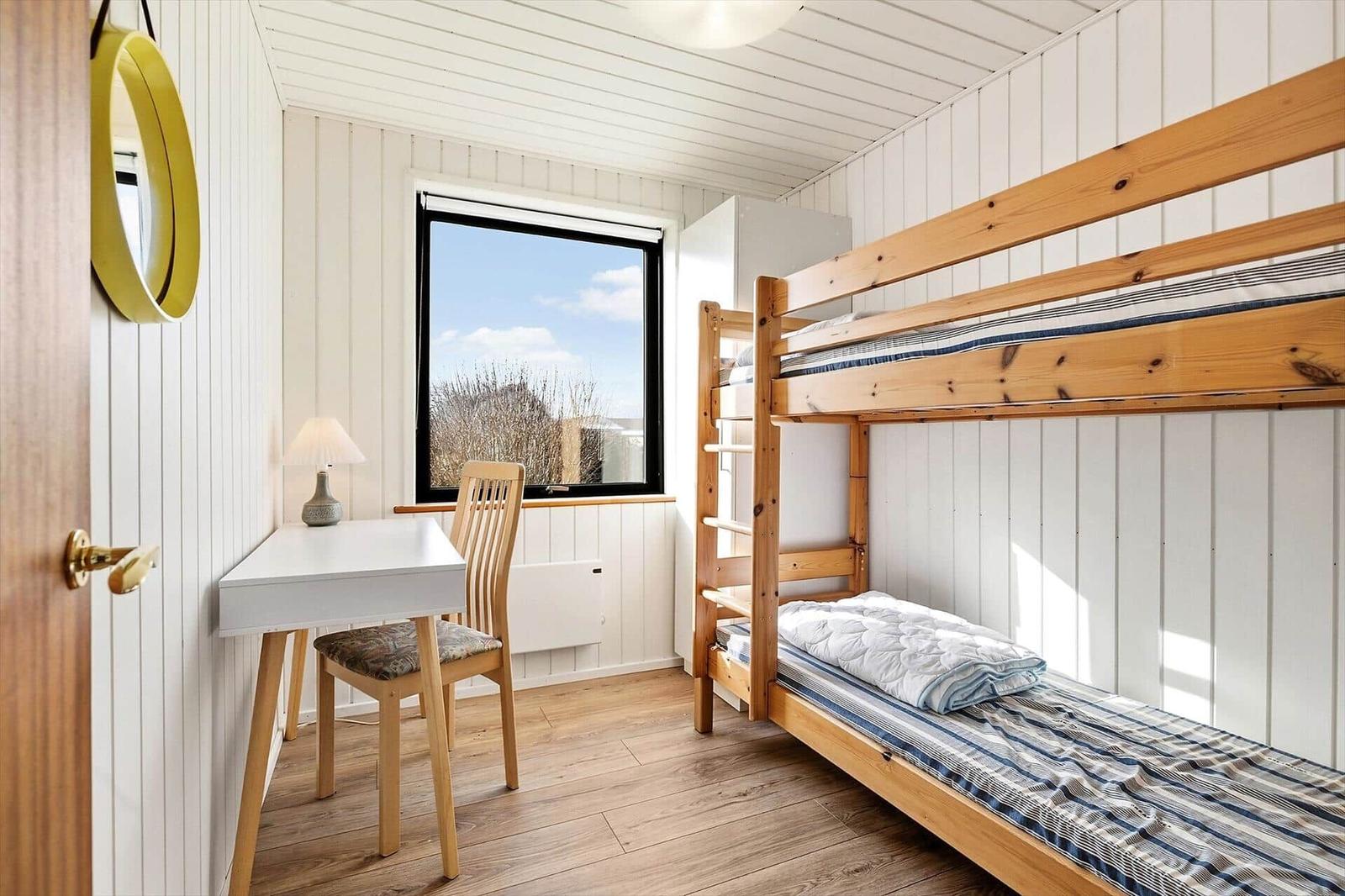 Zimmer mit Doppelstockbett, Schreibtisch und Fenster mit Blick.