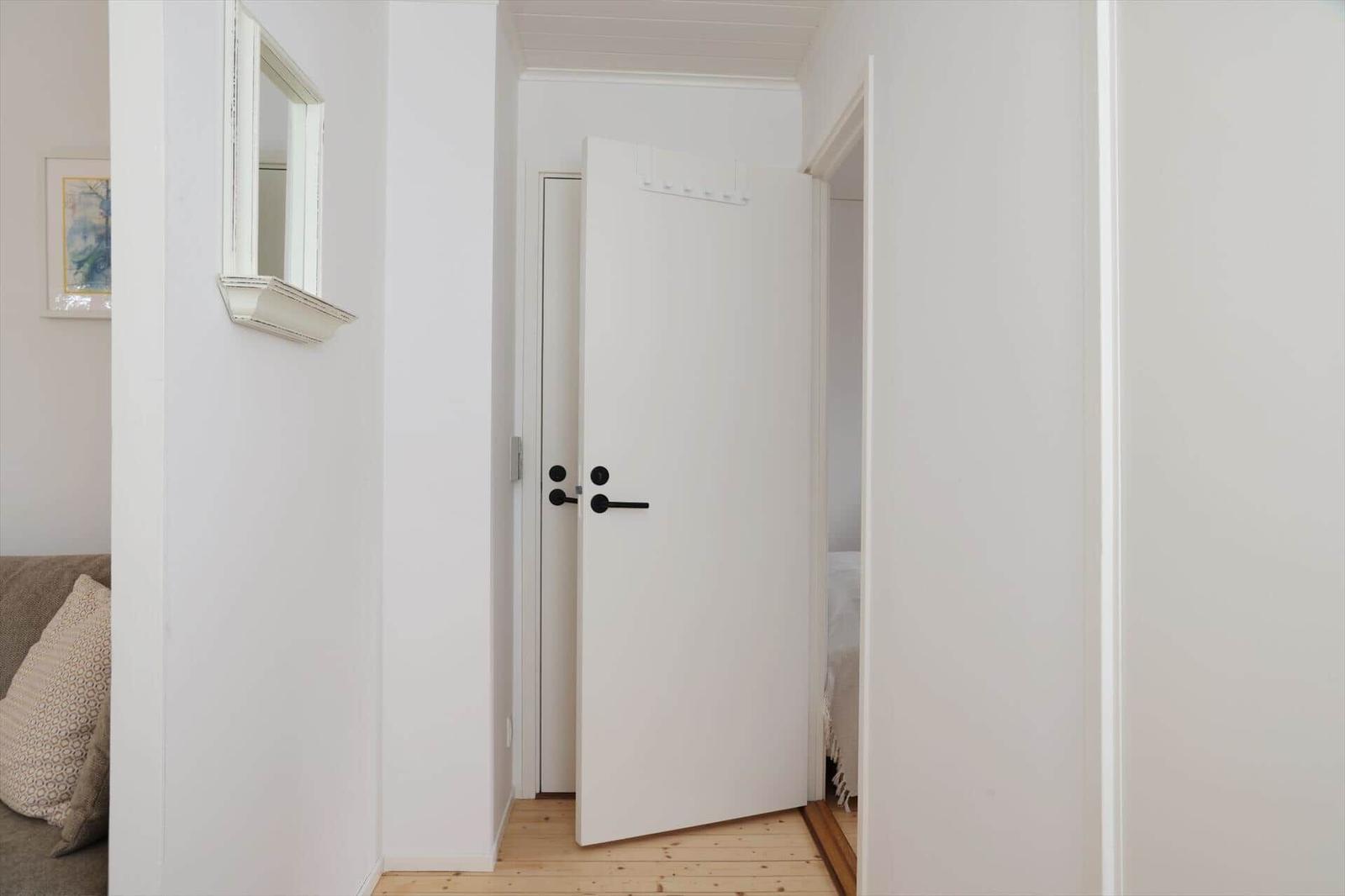 White doorway with wooden floor and mirror on the wall.