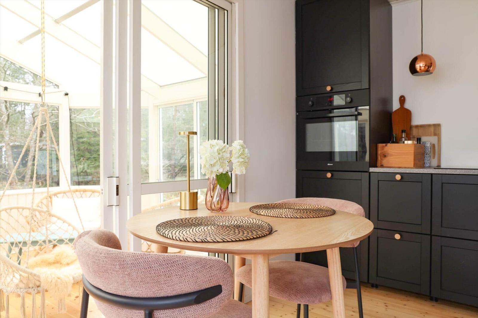 Round table with chairs, kitchen unit, and view to terrace with hanging chair.