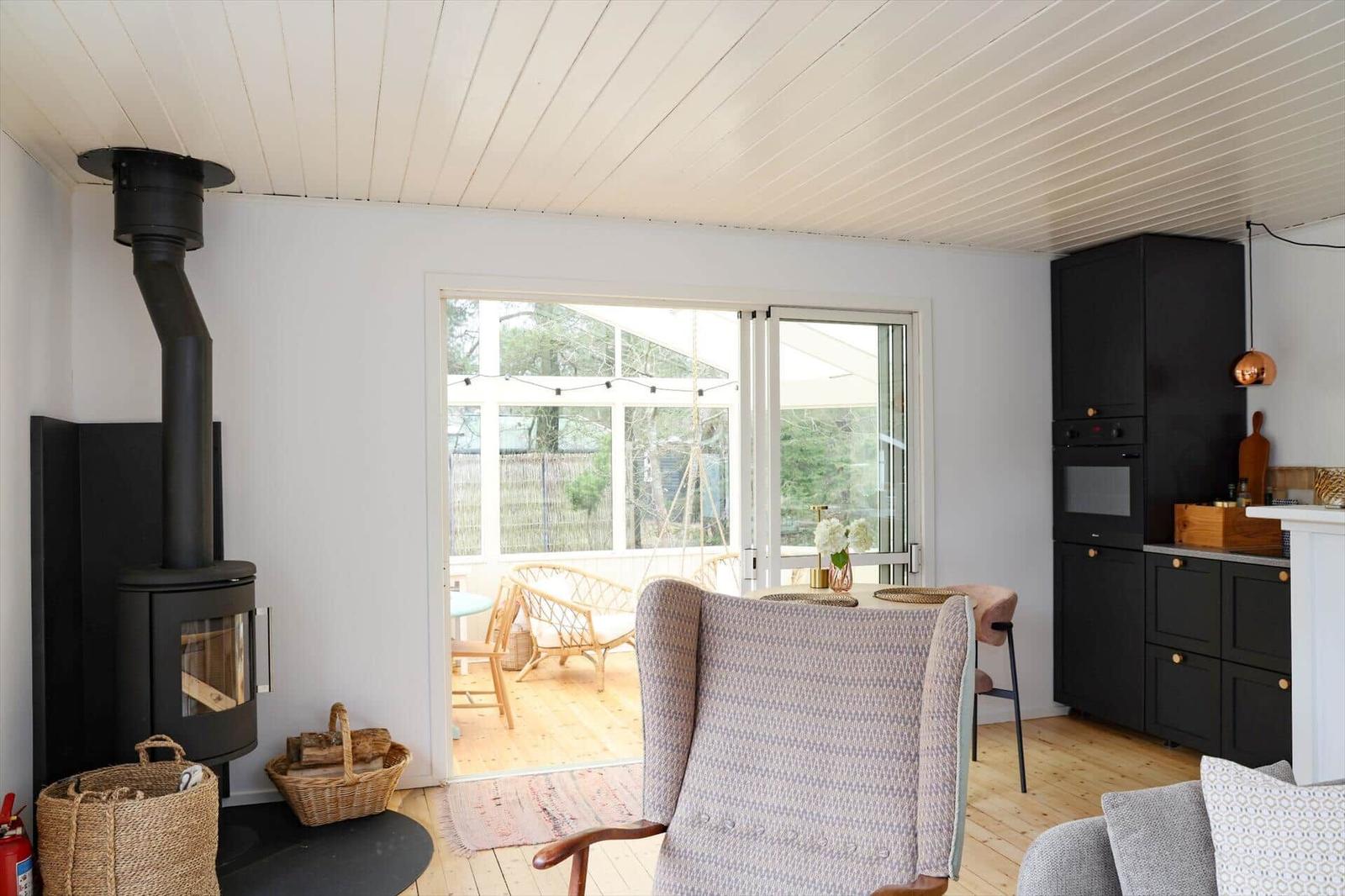 Room with fireplace, dining area, and kitchen. Passage to terrace with seating.