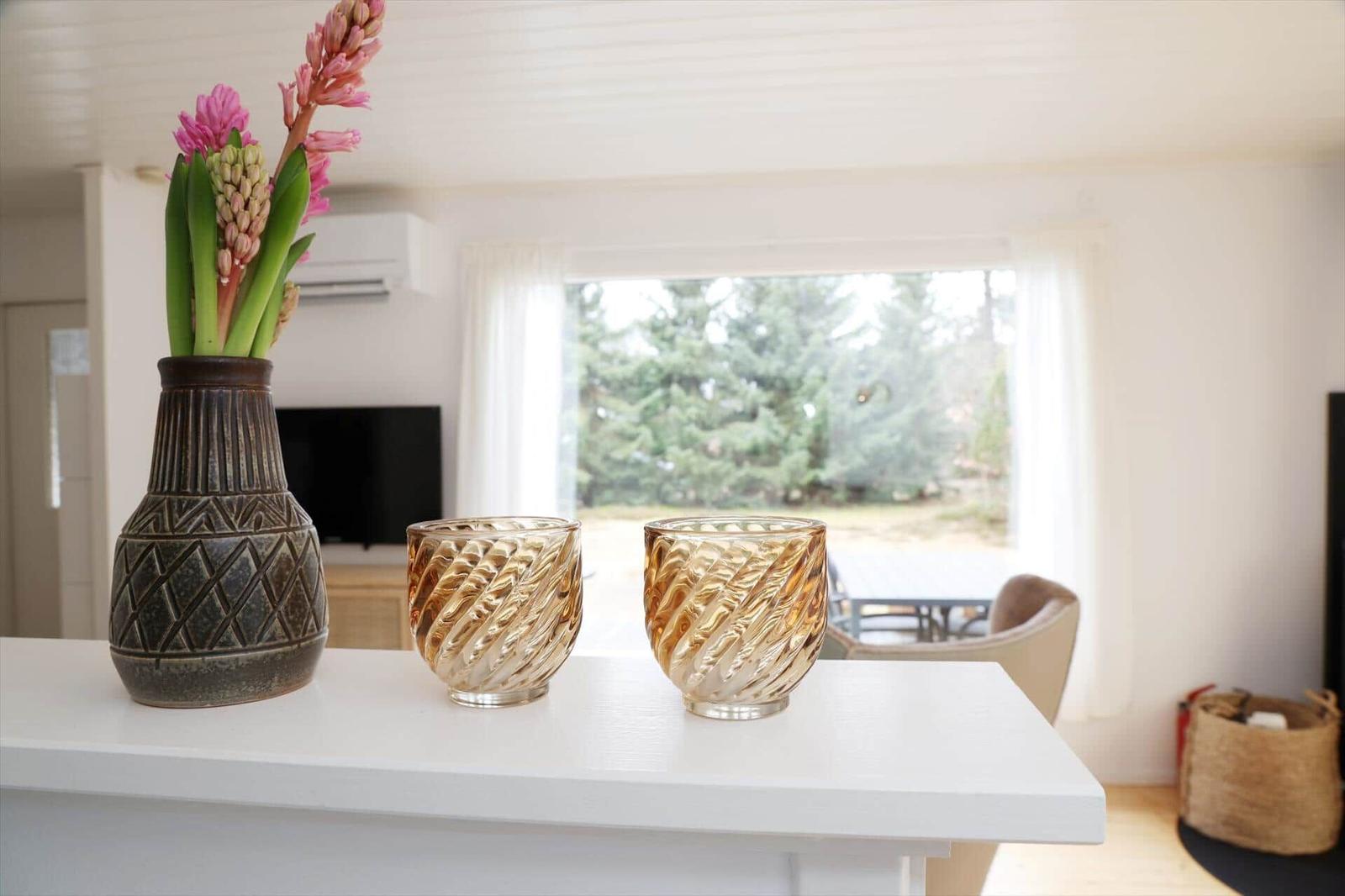 On the countertop are vases with flowers and two glasses.