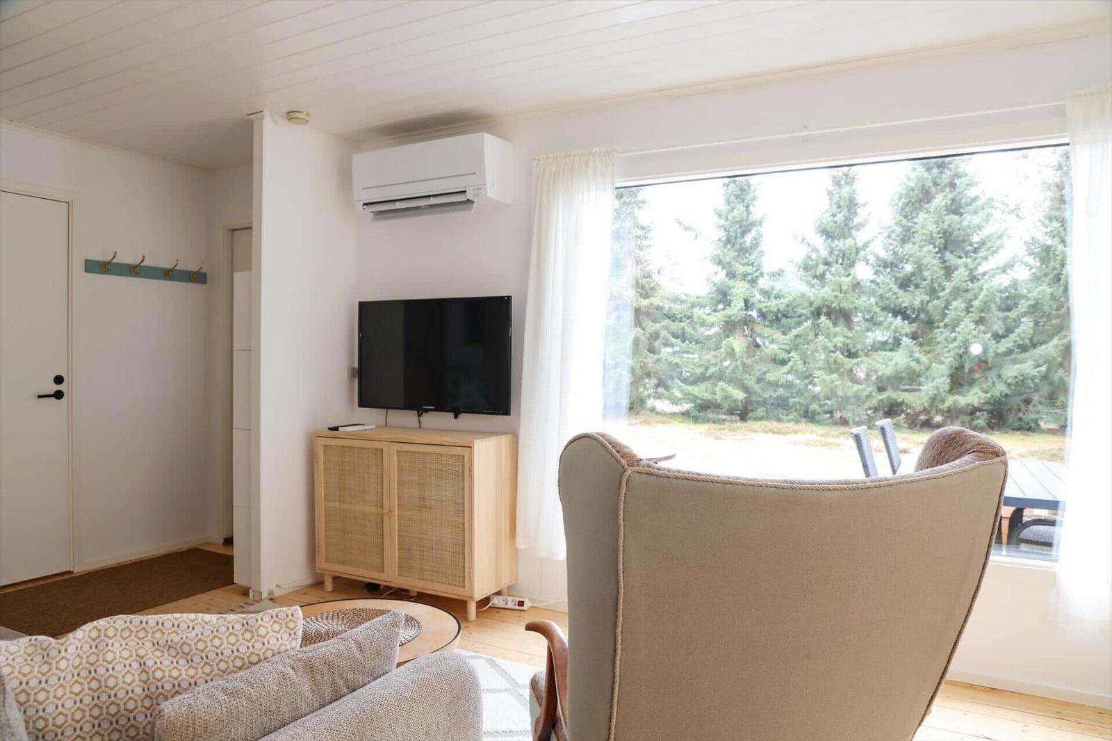Living room with TV, armchair, and view of forest.