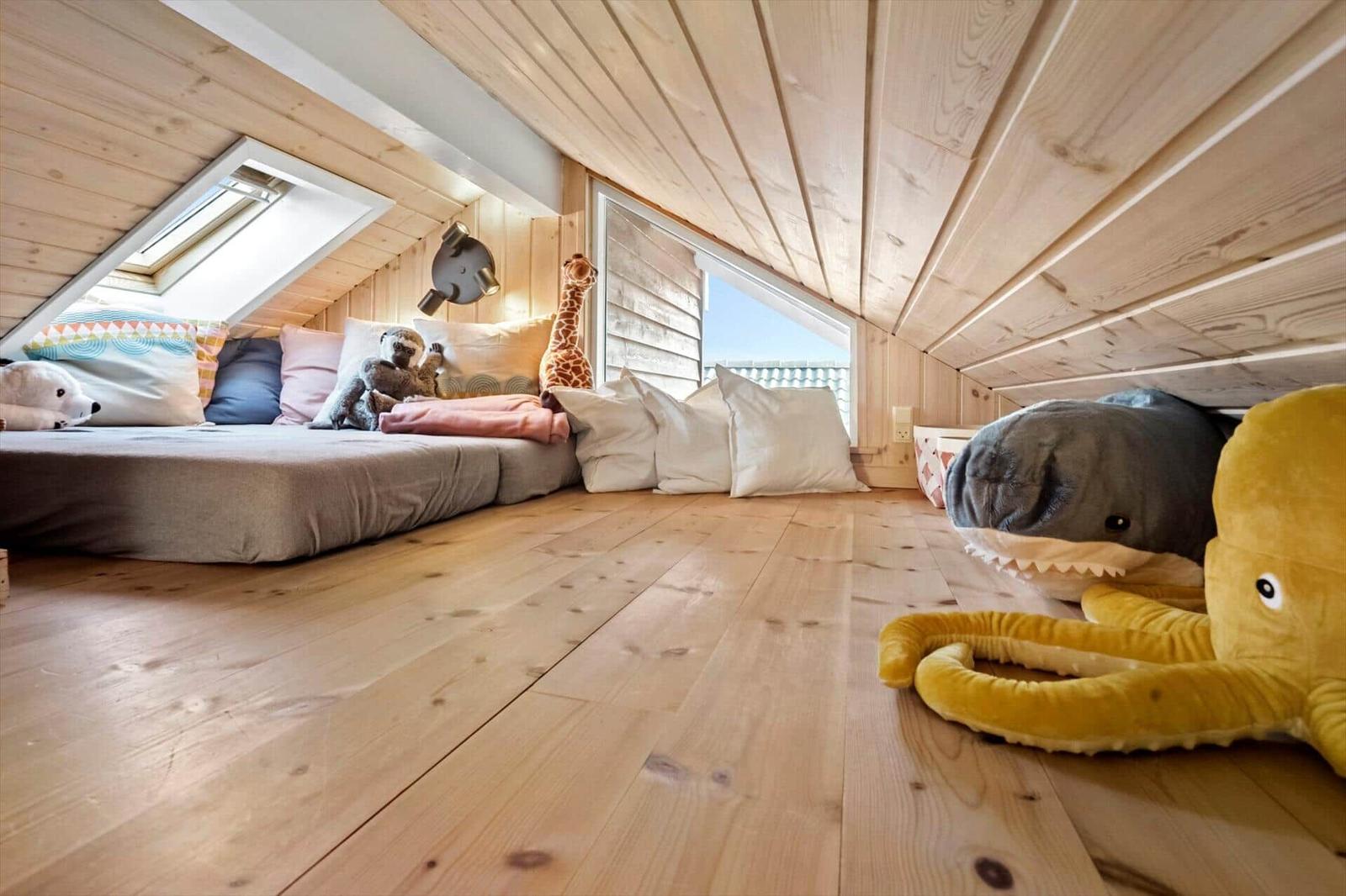 Attic room with wooden floor, window, and toys.