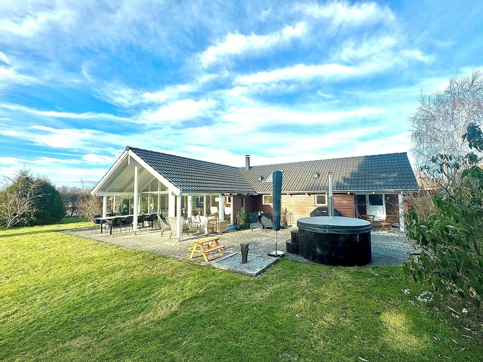 House with terrace, hot tub, and garden under blue sky.