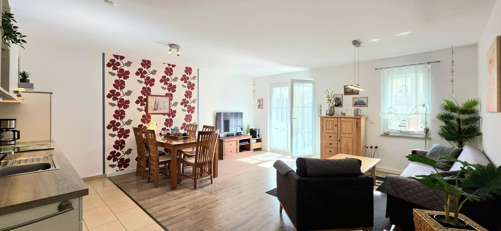 Wohnbereich mit Essbereich, Küche und Wohnzimmer mit Holzmöbeln und Pflanzen.