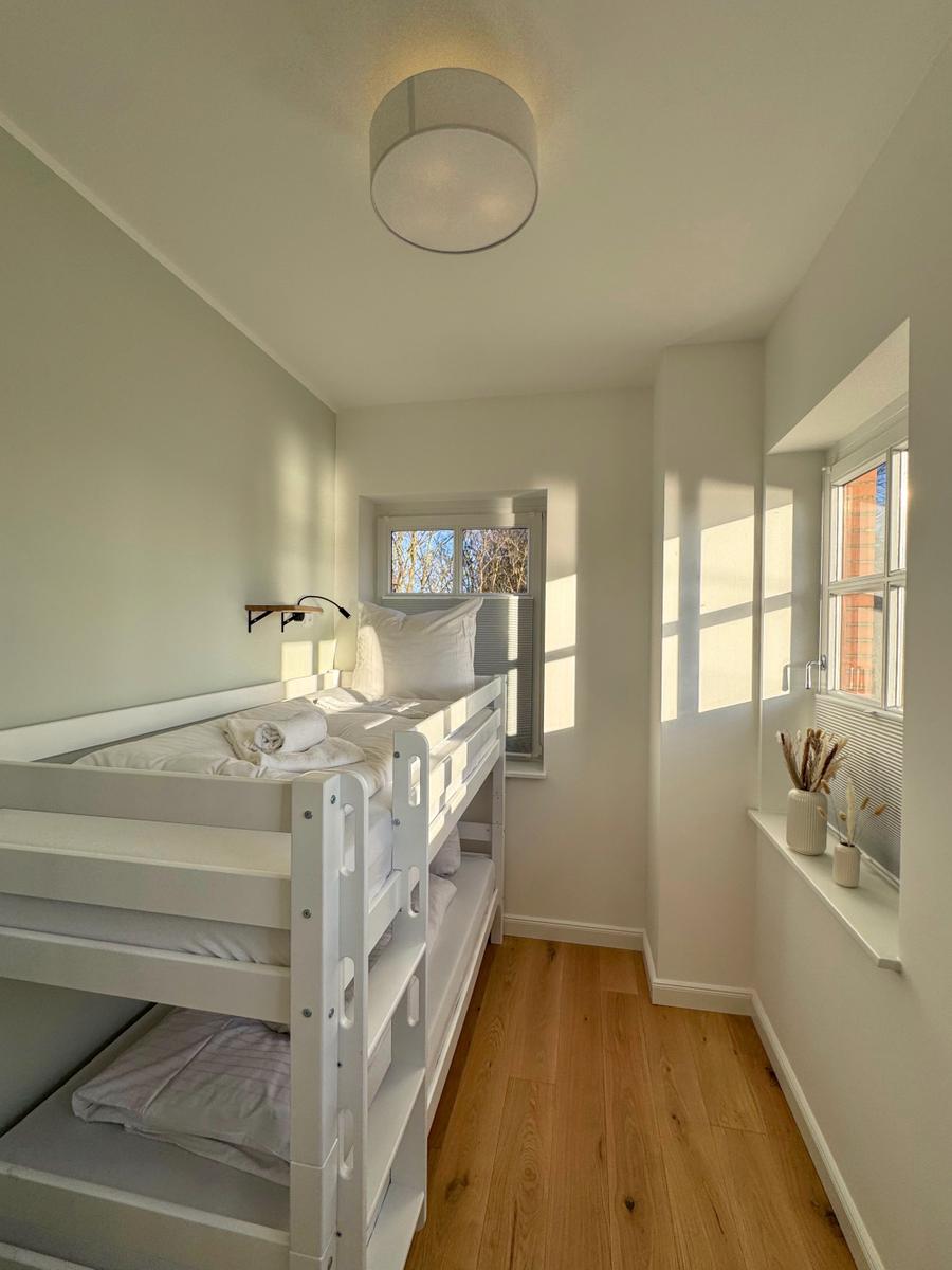 Zimmer mit Doppelstockbett, Holzboden und Fenstern mit Blick.