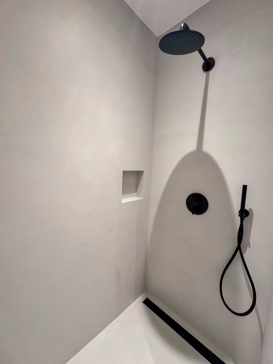 Dusche mit schwarzer Duschkopf und Handbrause, integrierte Ablage und schlichter Boden