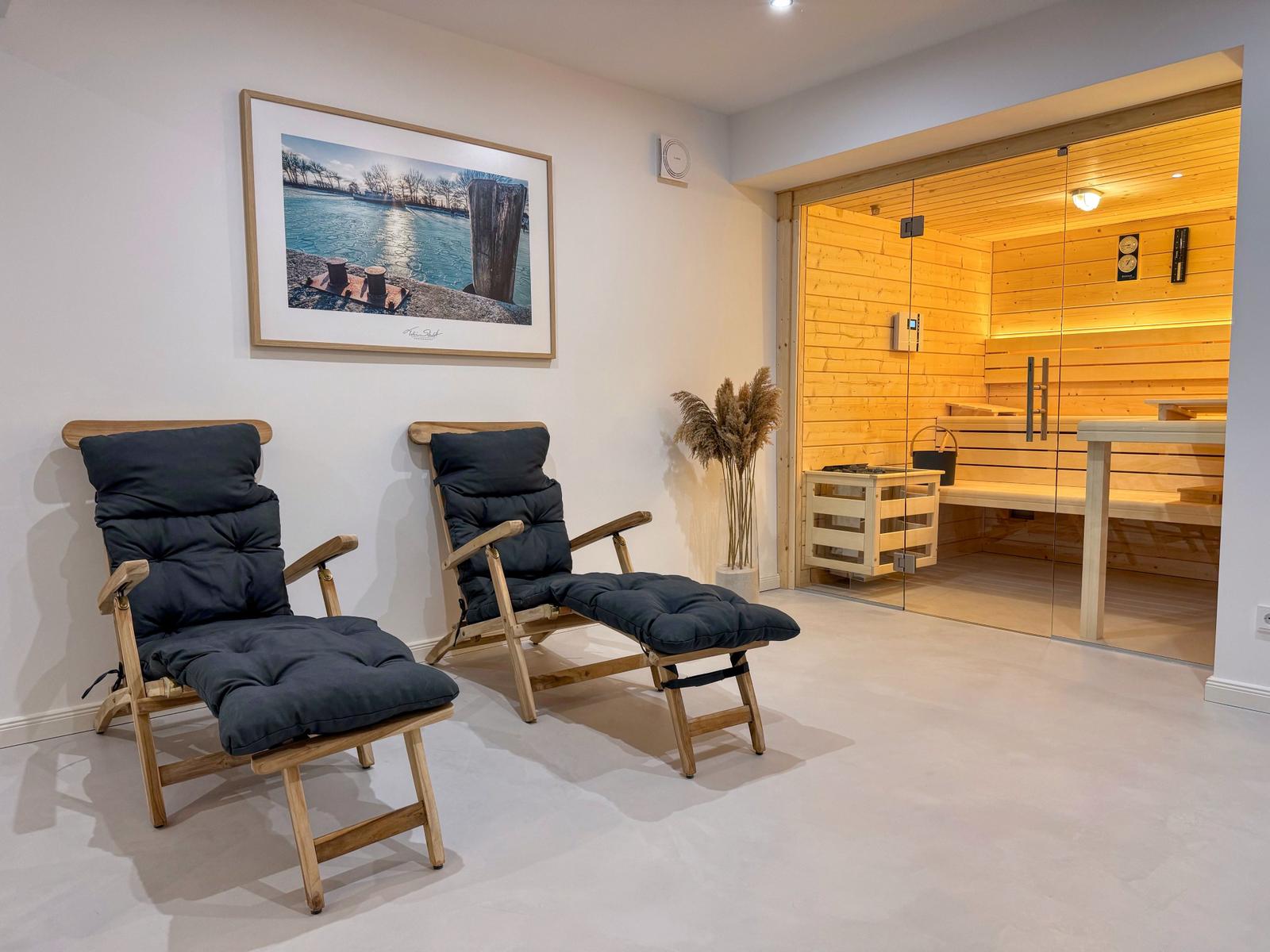 Zwei Holzstühle mit Kissen vor einer Sauna mit Glasfront.