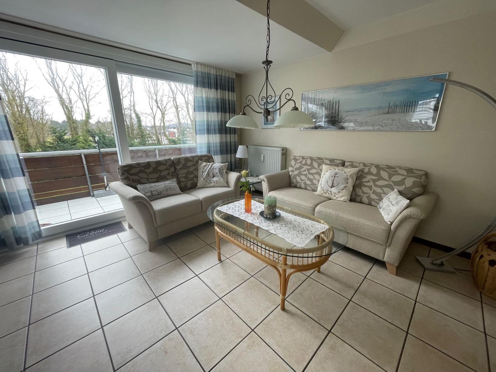 Wohnzimmer mit zwei Sofas, Glas-Tisch und Balkonansicht.