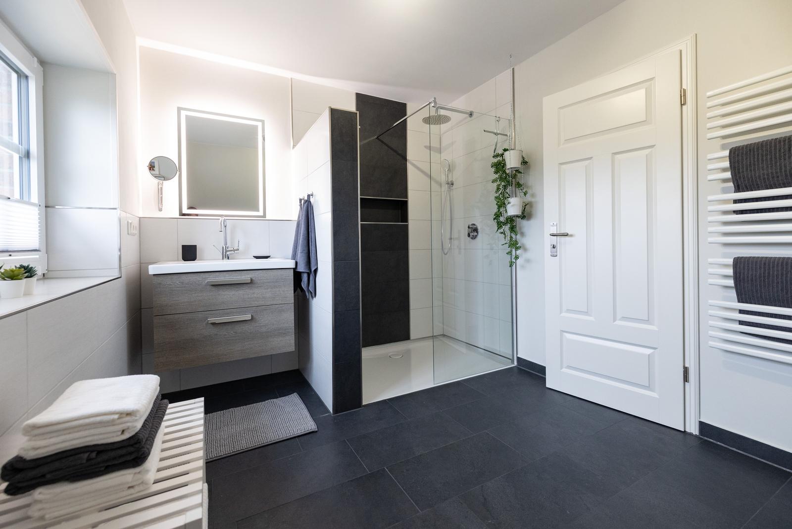 Badezimmer mit Dusche, Waschbecken und Heizung.