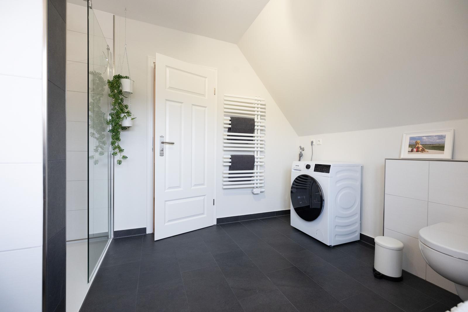 Badezimmer mit Dusche, Waschmaschine und Heizkörper