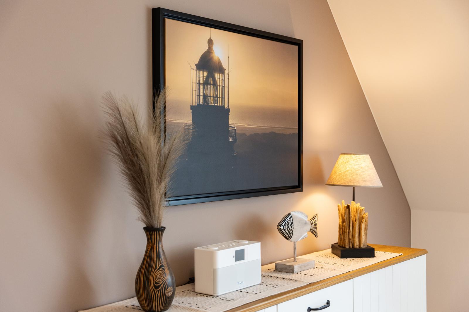 Wandbild mit Leuchtturm, Lampe und Dekoration auf Schrank