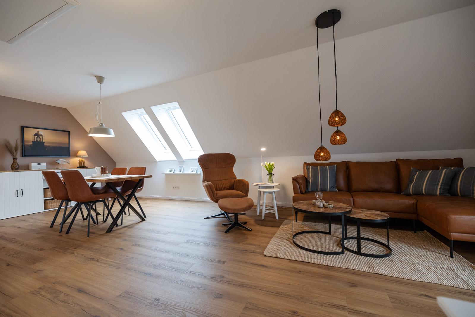 Wohn- und Essbereich mit braunem Sofa, Esstisch und Dachfenstern.