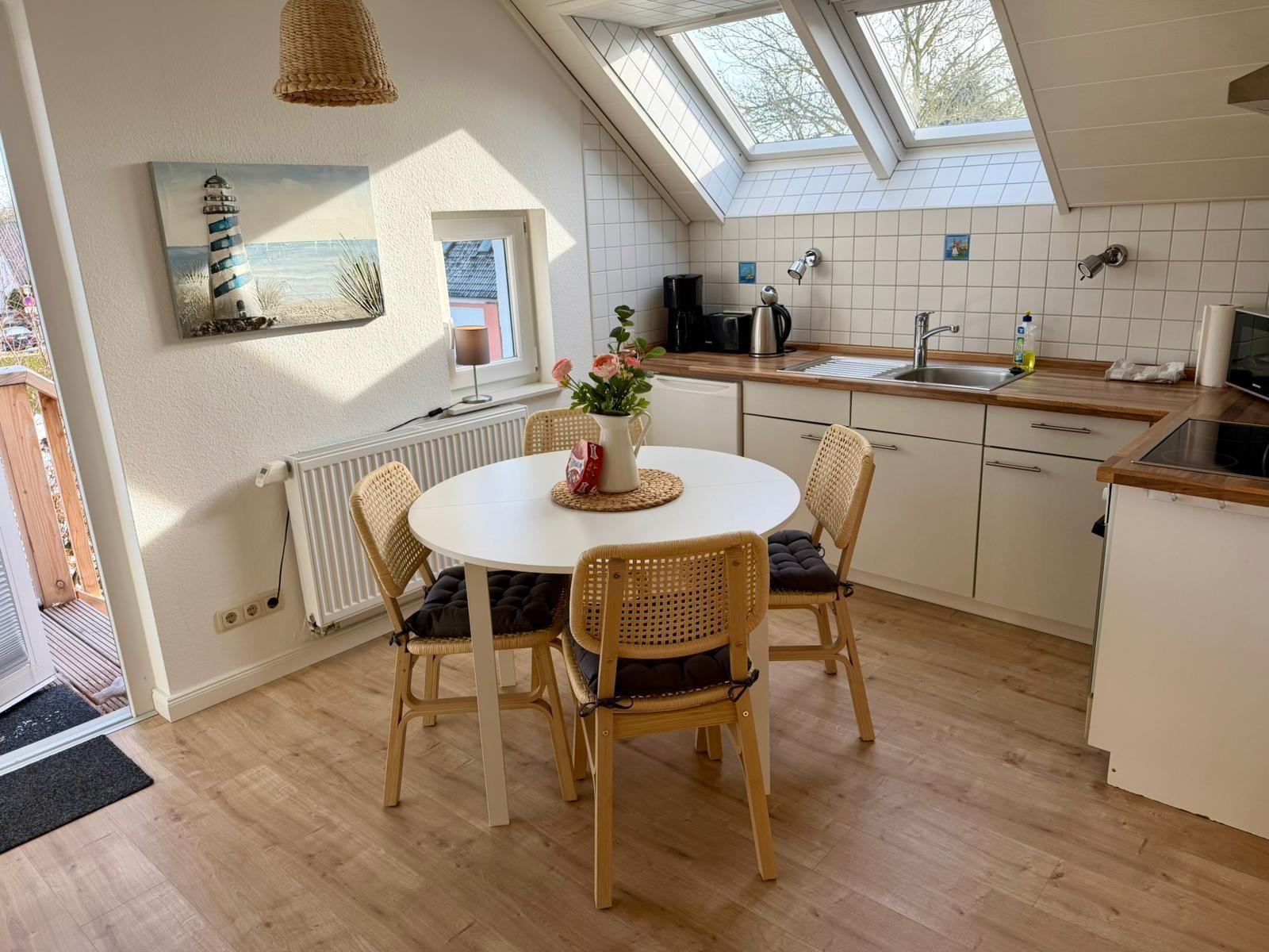 Küche mit Essbereich, Dachfenster und Holzboden. Tisch mit vier Stühlen.