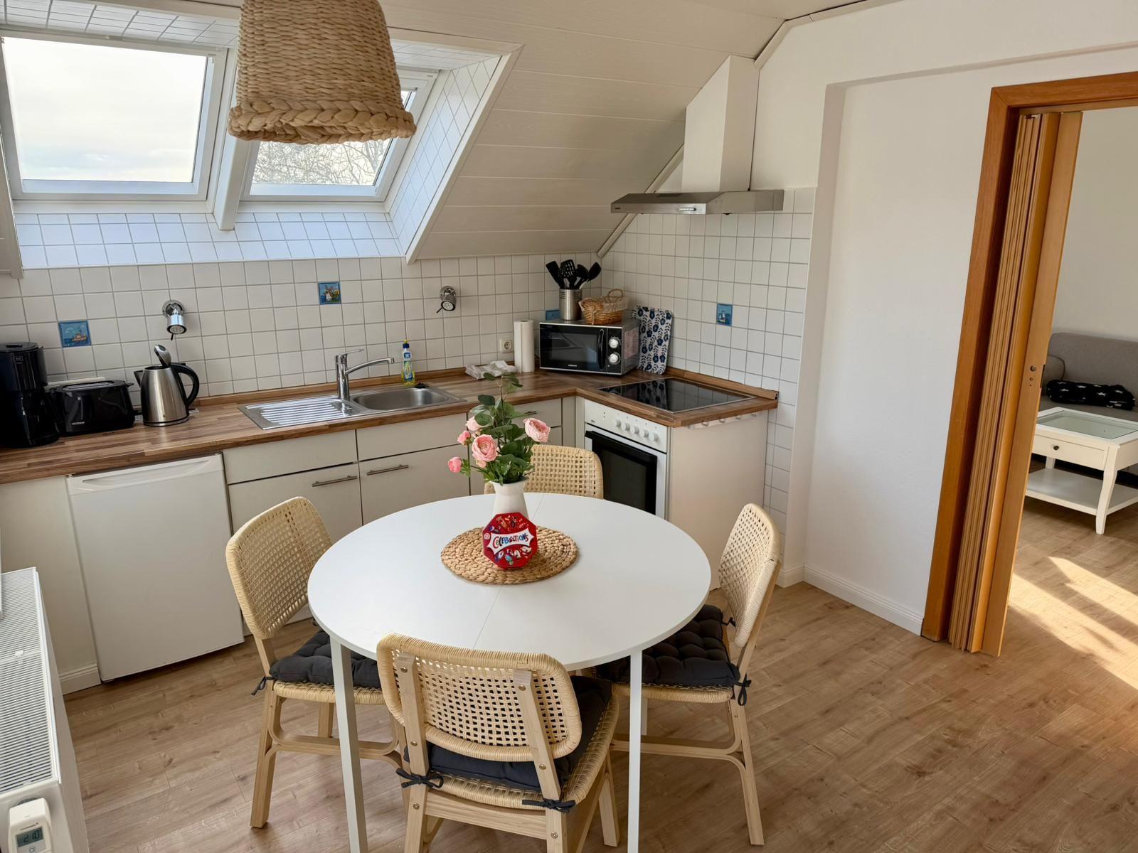 Küche mit Essbereich, Dachfenster und Holzboden. Runde Tisch mit Stühlen.