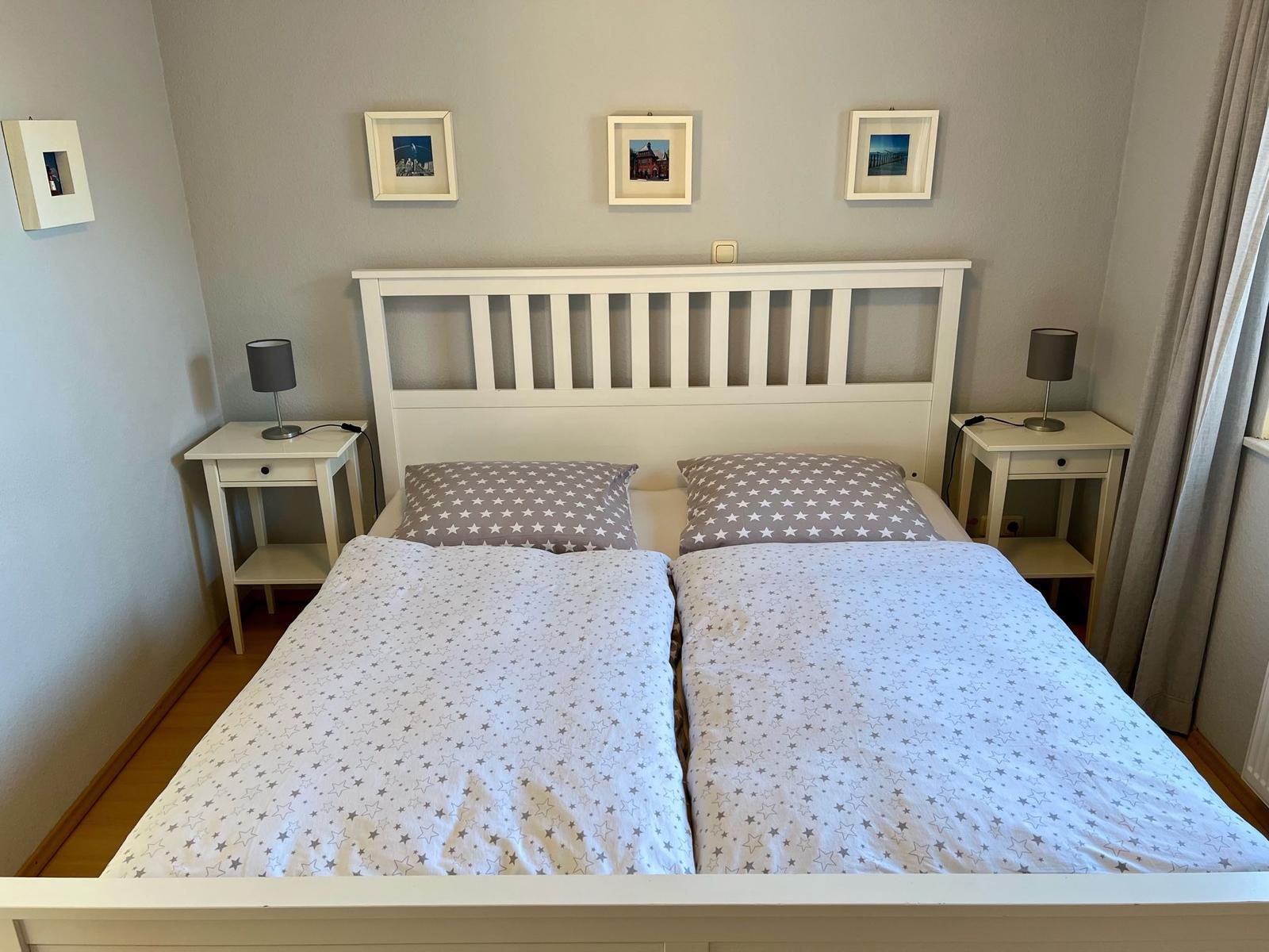 Schlafzimmer mit Doppelbett, zwei Nachttischen und Wandbildern.