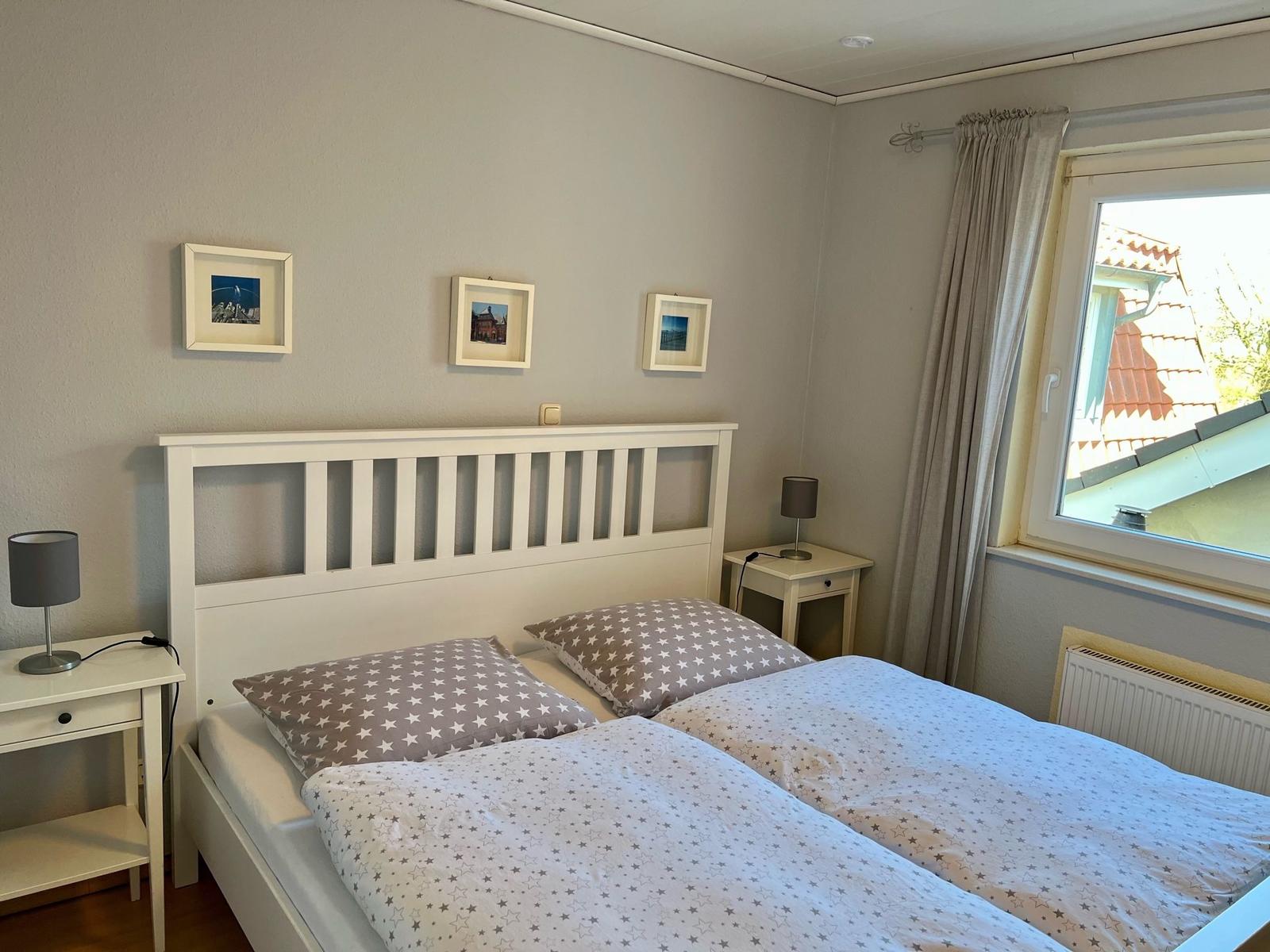 Schlafzimmer mit Doppelbett, zwei Nachttischen und Fenster mit Blick auf Dach