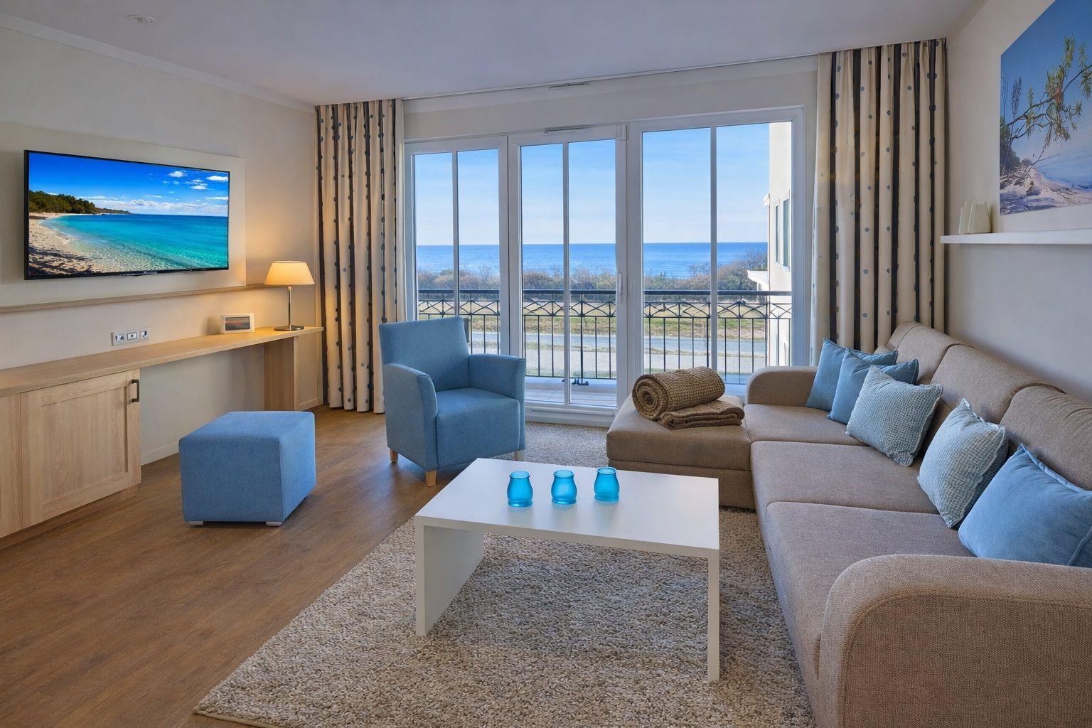 Wohnzimmer mit Sofa, Sessel und Balkonblick aufs Meer.