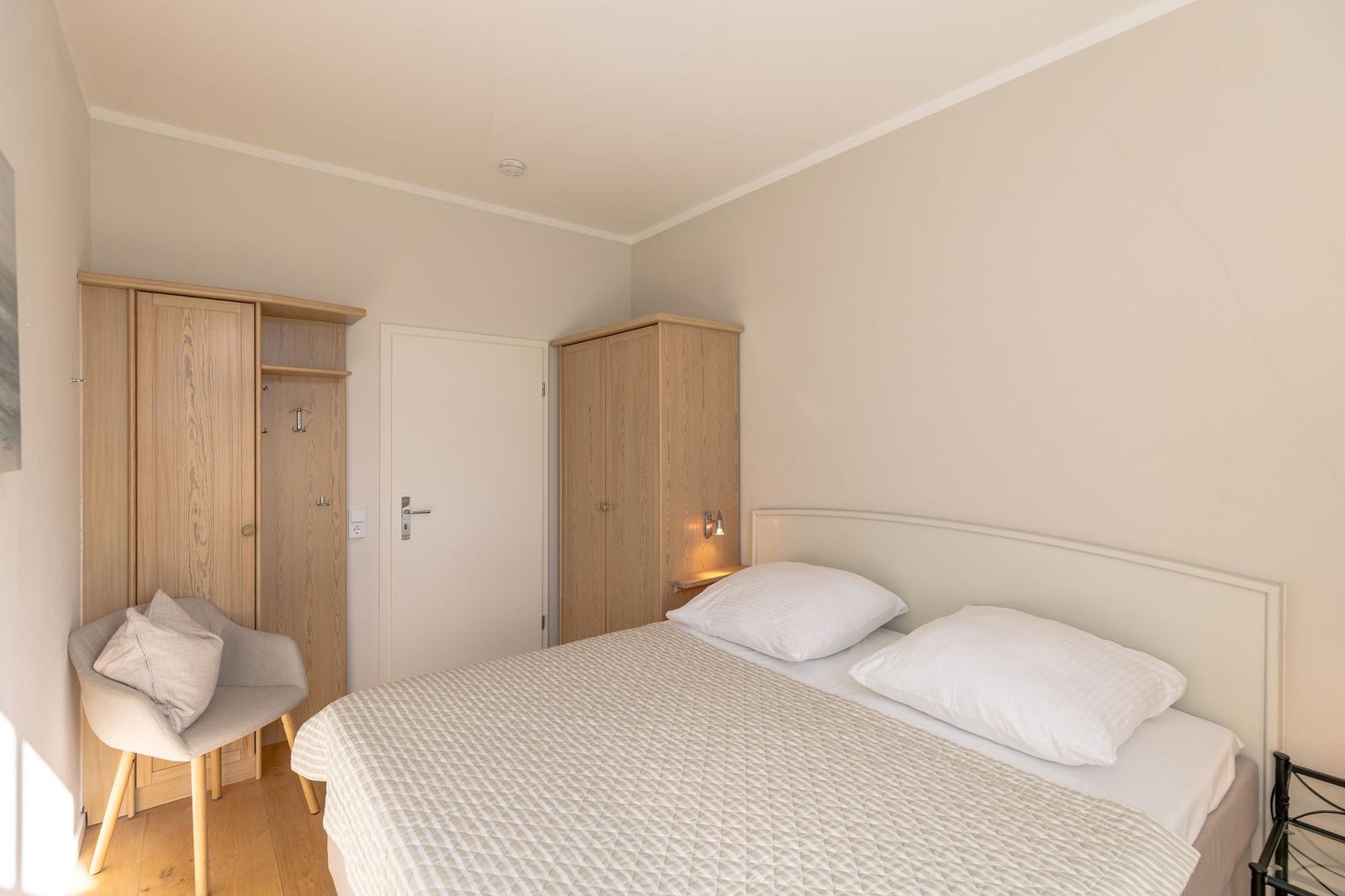 Schlafzimmer mit Bett, Fenster, Lampe und Wandbild.