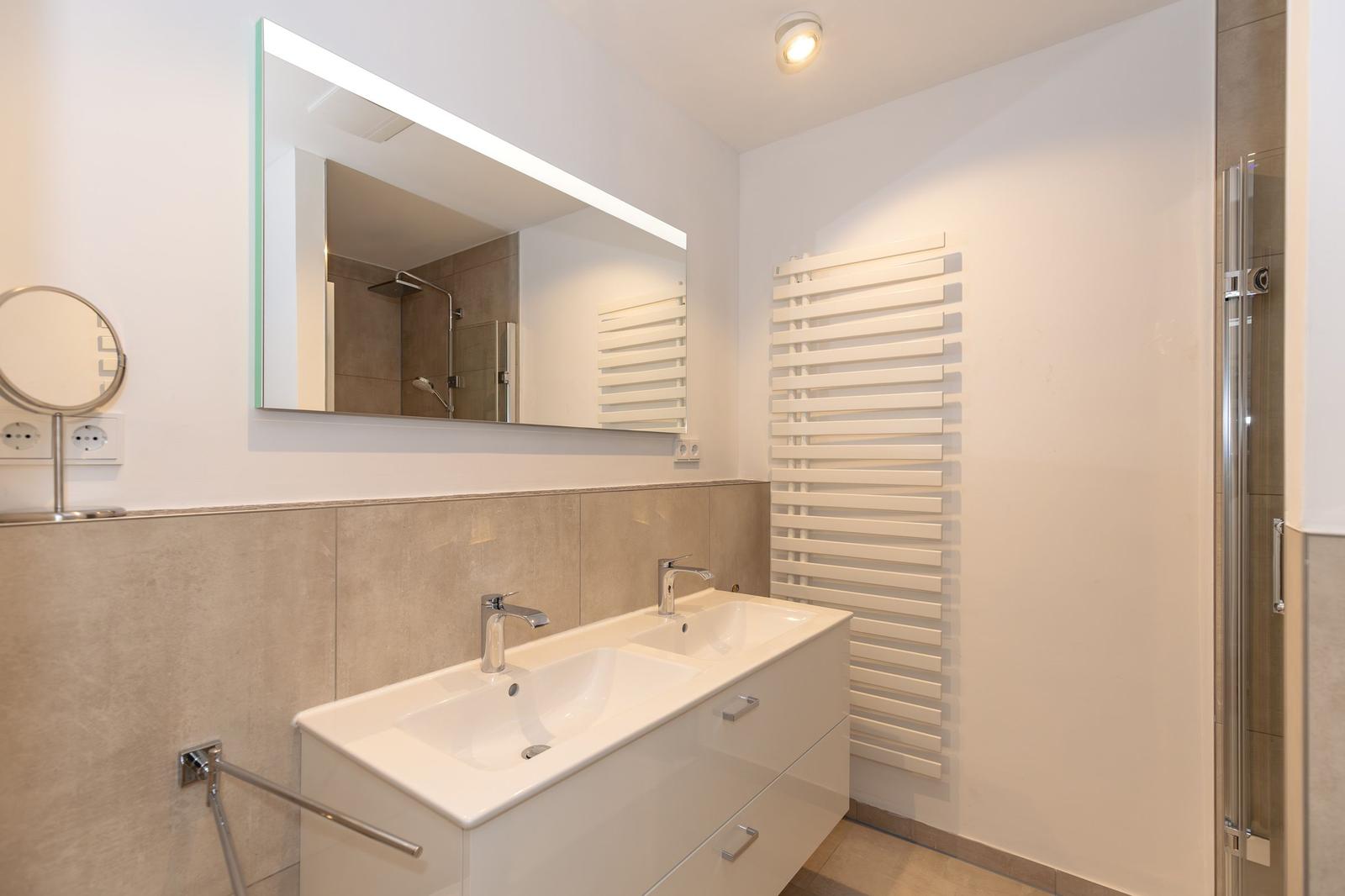 Flur mit Garderobe und Blick in Schlafzimmer mit Holzboden und Wandbild.