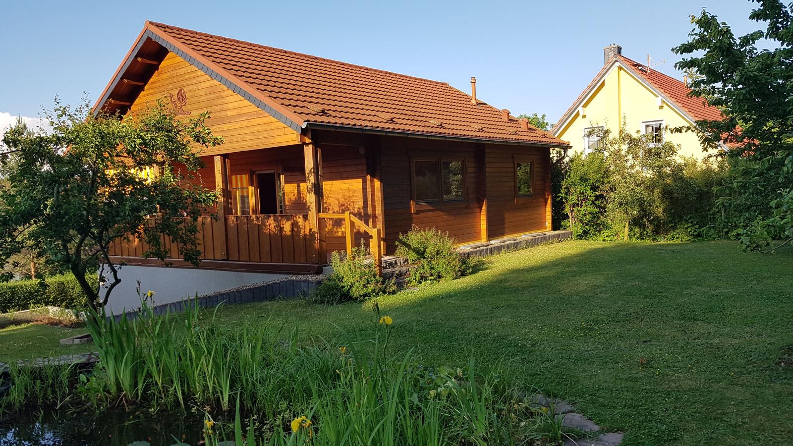 Holzhaus mit Balkon, Garten und Teich. Hinterhof mit gelbem Haus.