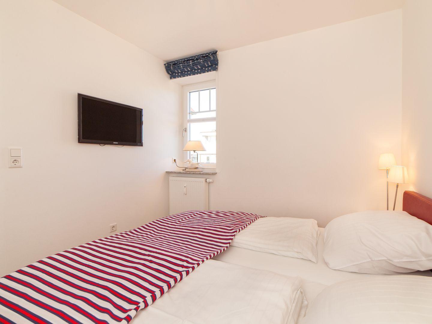 Schlafzimmer mit Bett, TV und Fenster