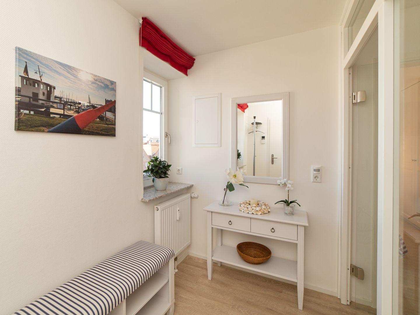 Eingangsbereich mit Spiegel, Schrank und Fenster. An der Wand hängt ein Bild mit Segelboot.