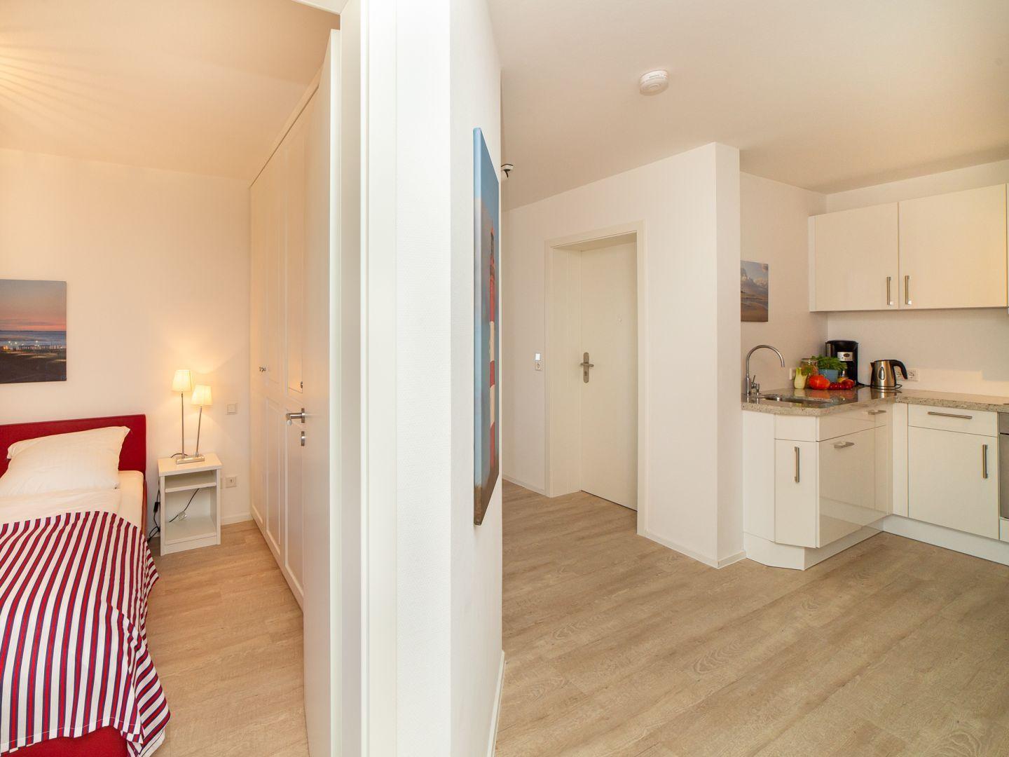 Schlafzimmer mit Bett und Küchenbereich mit Arbeitsplatte und Schränken.