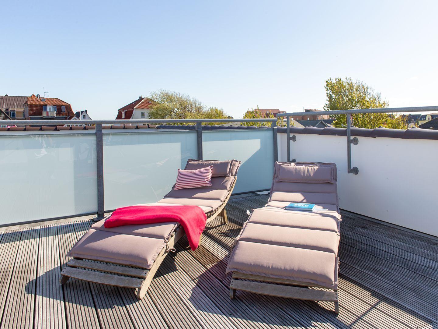 Dachterrasse mit zwei Liegestühlen und Blick auf die Stadt