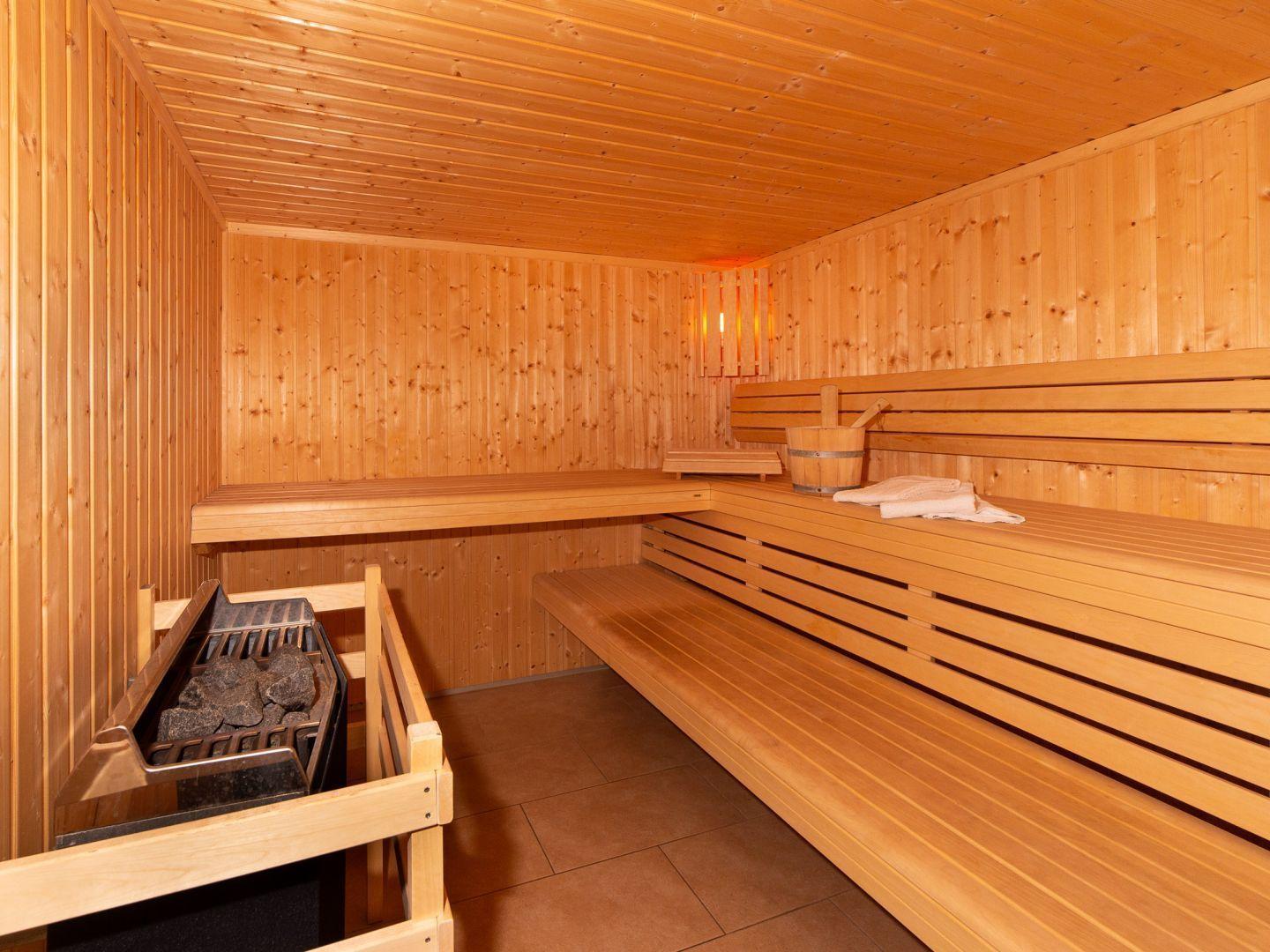 Holzsauna mit Sitzbänken, Holzofen und Eimer