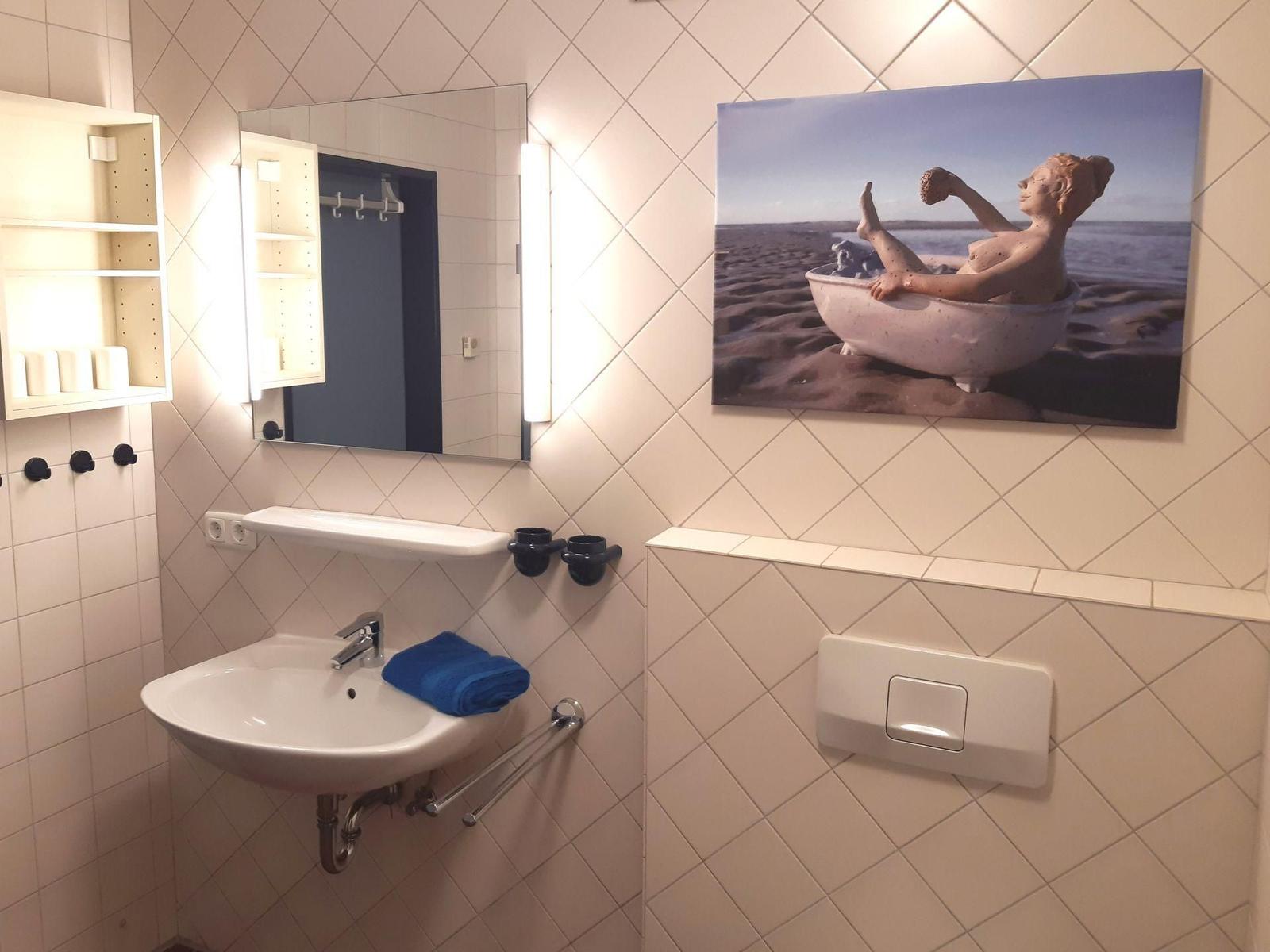 Badezimmer mit Waschbecken, Spiegel und Wandbild.