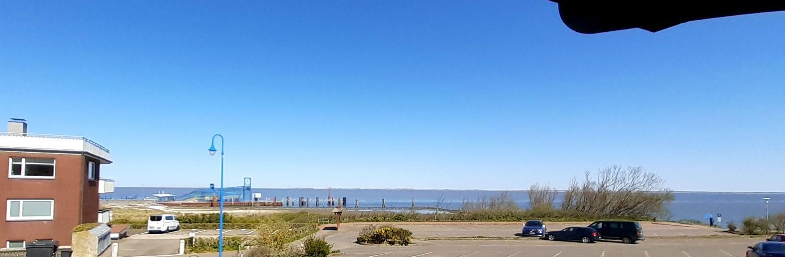 Parkplatz mit Blick aufs Wasser und einen roten Gebäudeblock.