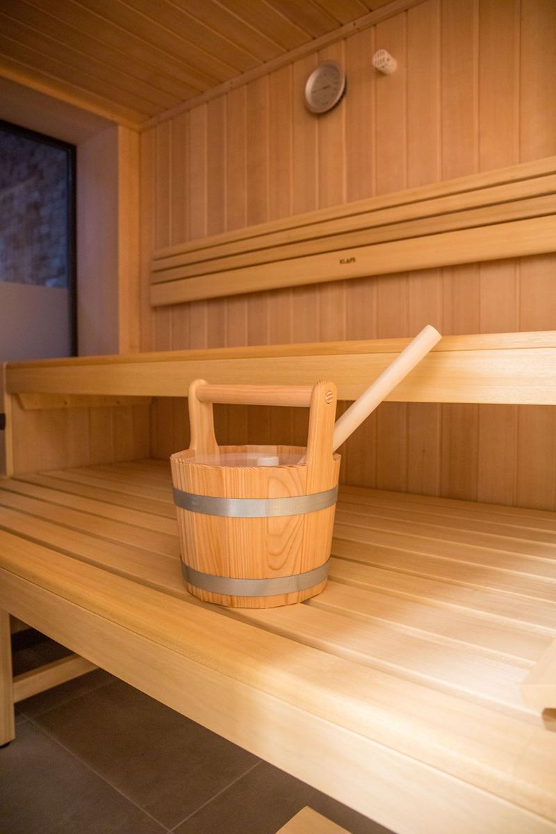 Sauna mit Holzbank und Eimer mit Löffel