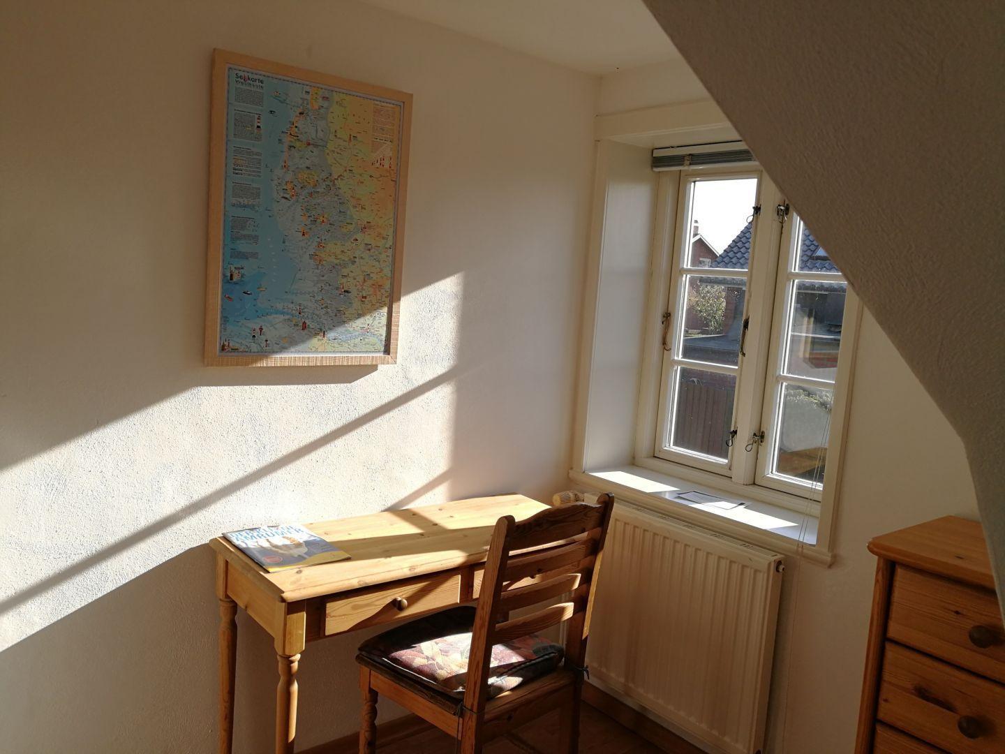 Ein Arbeitszimmer mit Schreibtisch, Stuhl und Karte an der Wand.