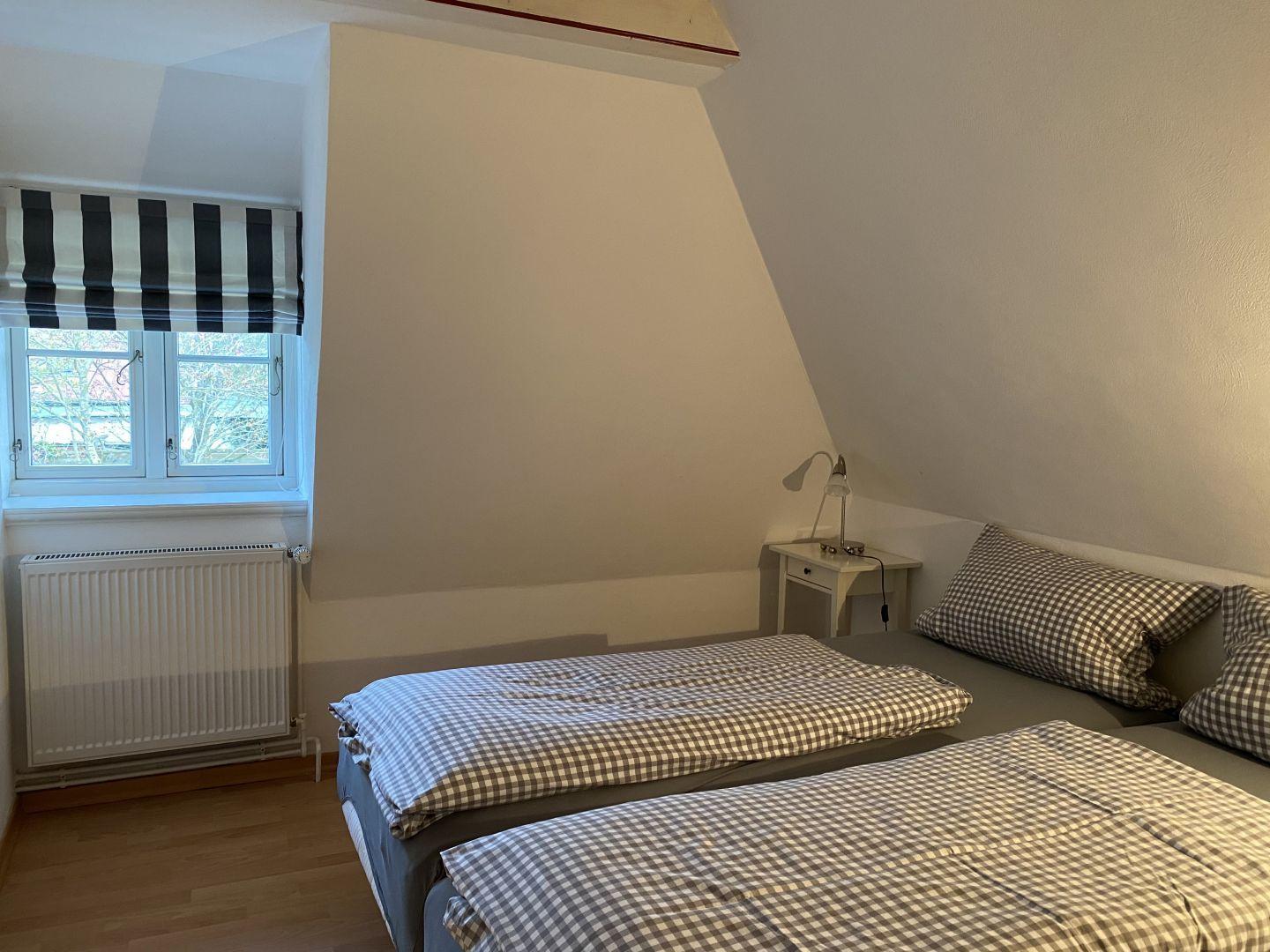 Schlafzimmer mit Doppelbett, Fenster und Nachttisch