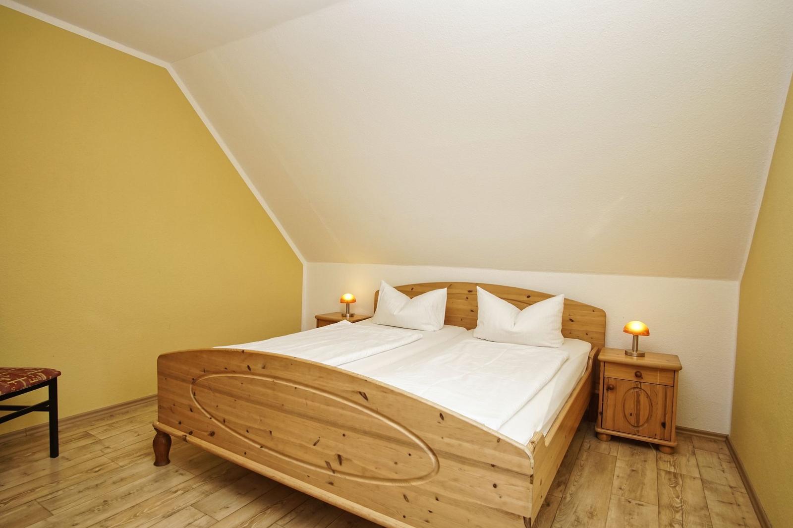 Schlafzimmer mit Holzbett, Nachttischen und gelber Wand.