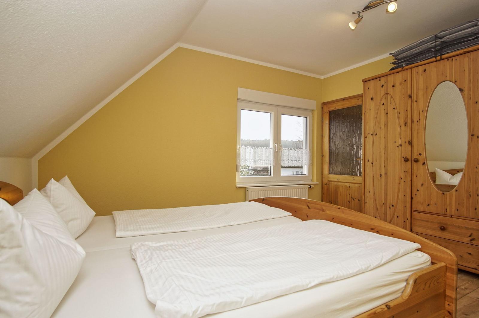 Schlafzimmer mit Dachschräge, Holzbett und Kleiderschrank