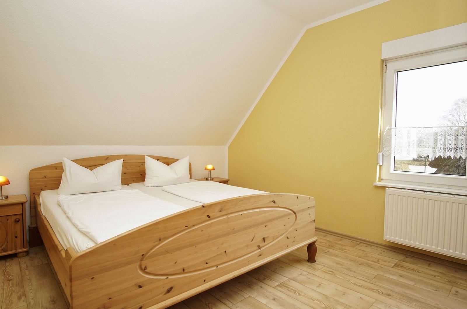 Schlafzimmer mit Holzbett, Fenster und Heizkörper