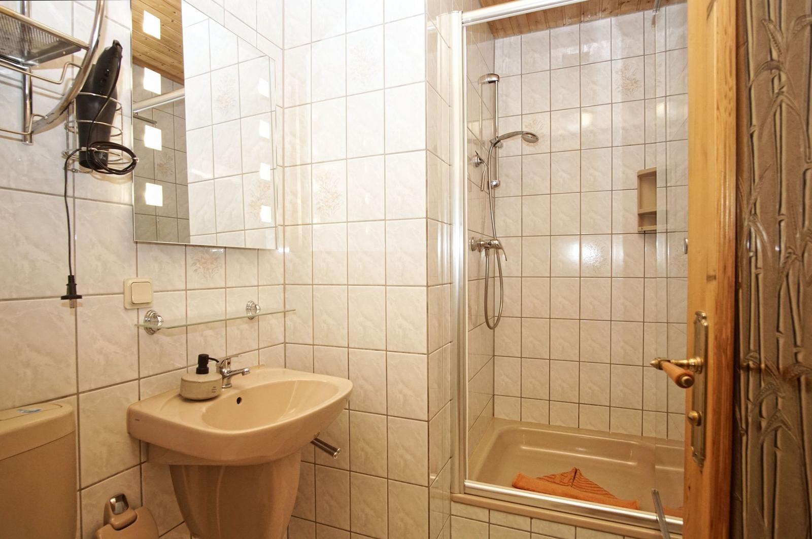 Bad mit Dusche, Waschbecken und Spiegel an der Wand