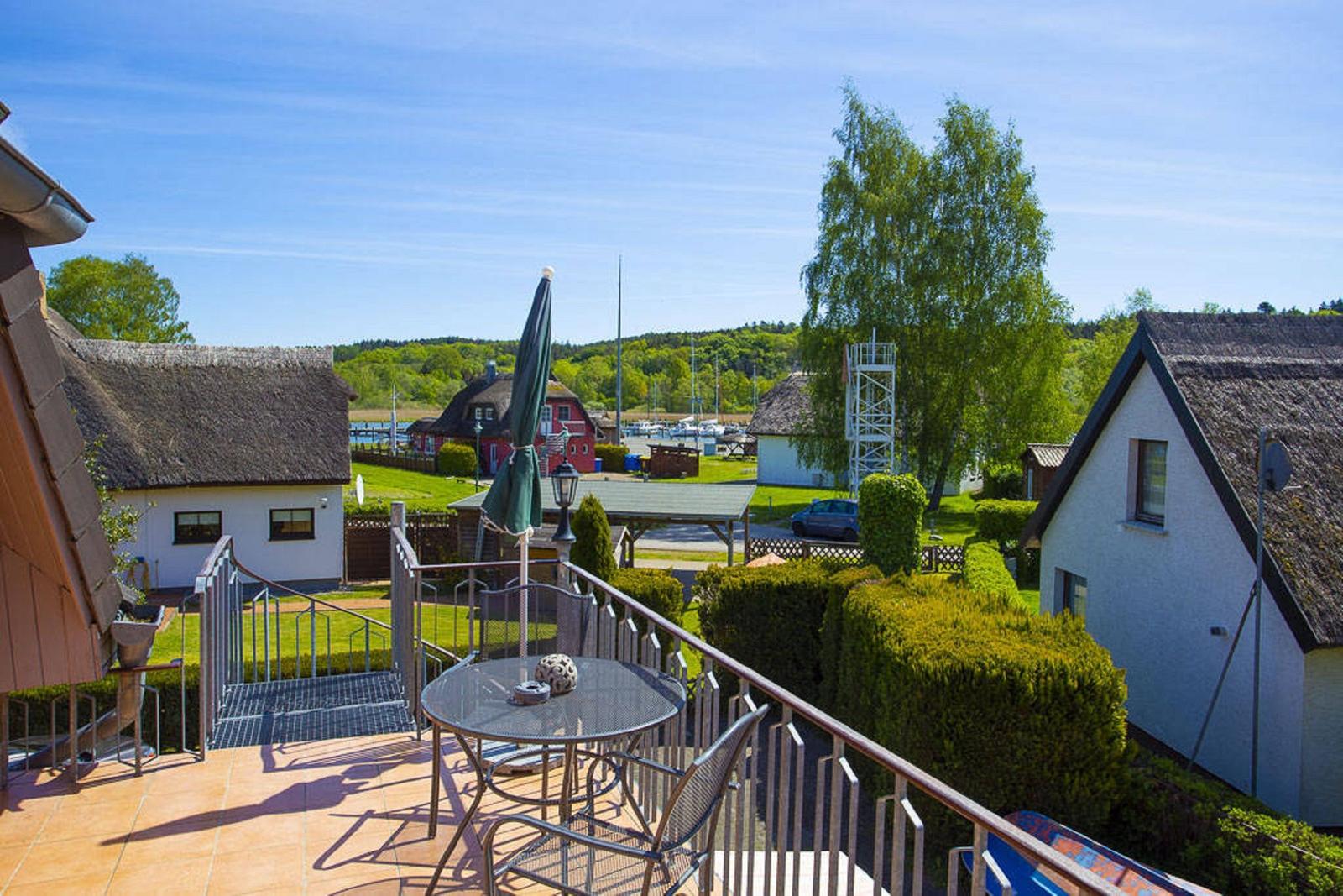 Terrasse mit Tisch und Stühlen, Blick auf Hütten und Hafen.