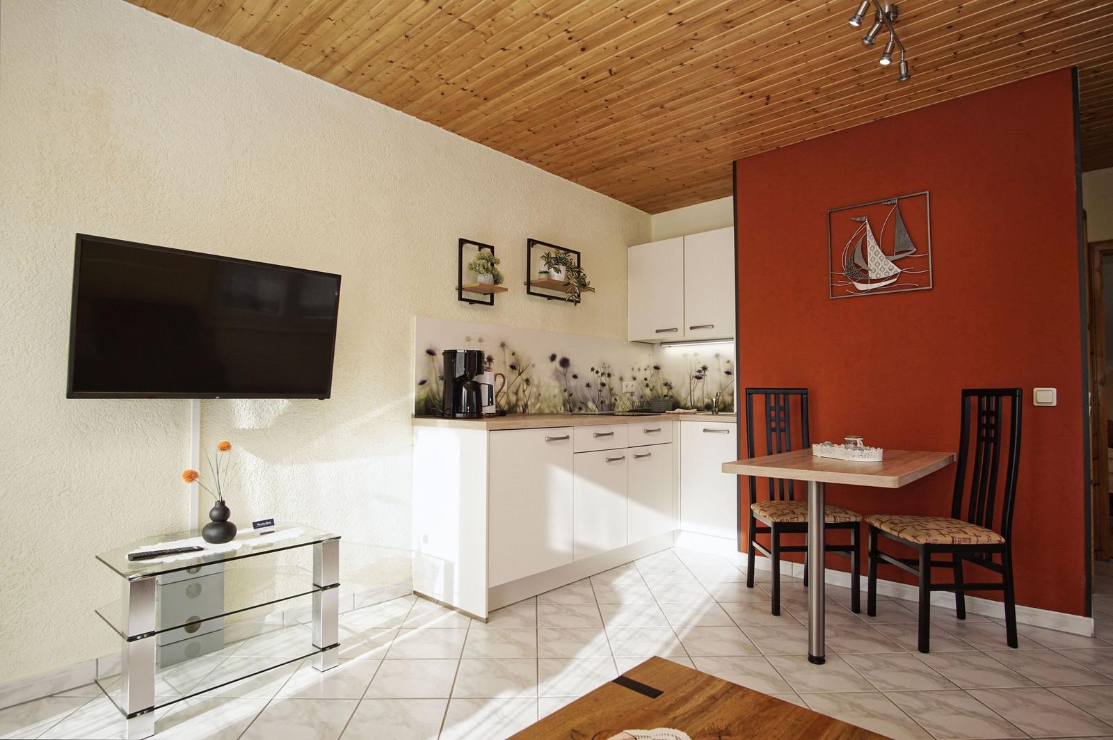 Küche mit Esstisch, Fernseher und Holzdecke.