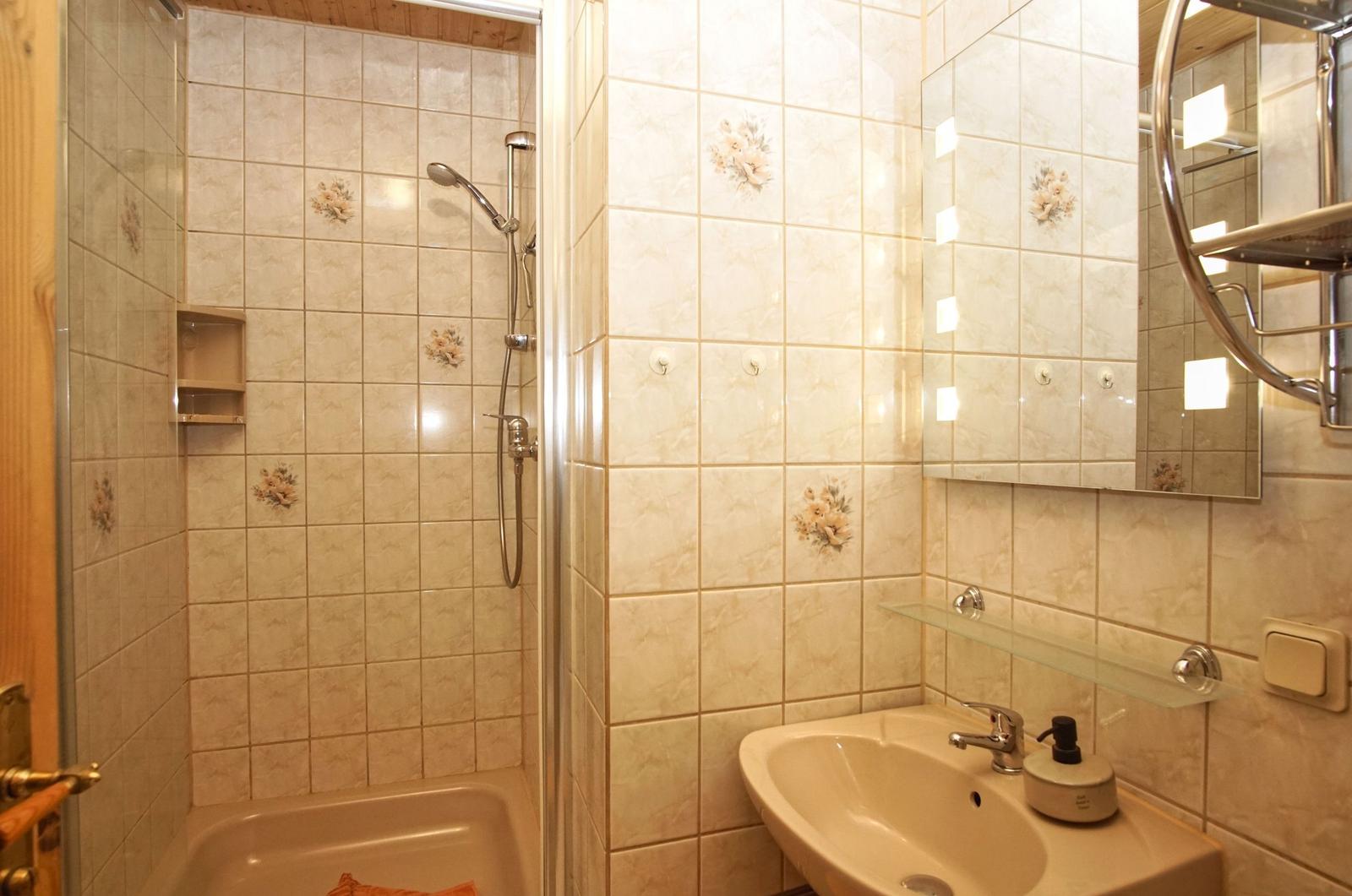 Badezimmer mit Dusche, Waschbecken und Spiegel