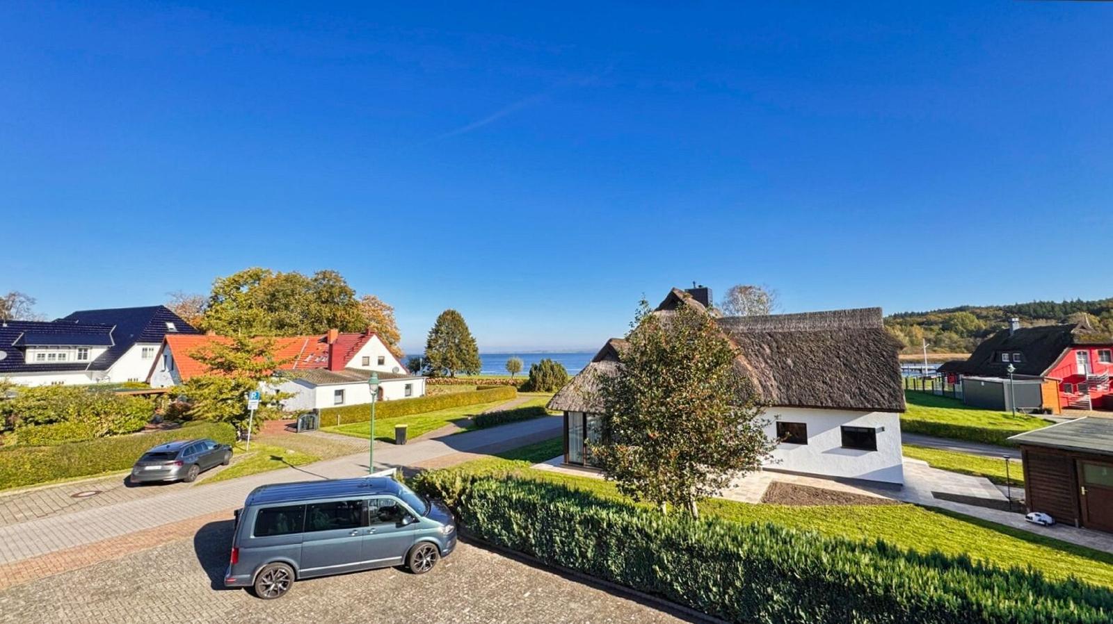 Wohnhaus mit Strohdach, gepflegter Garten und Blick aufs Wasser.