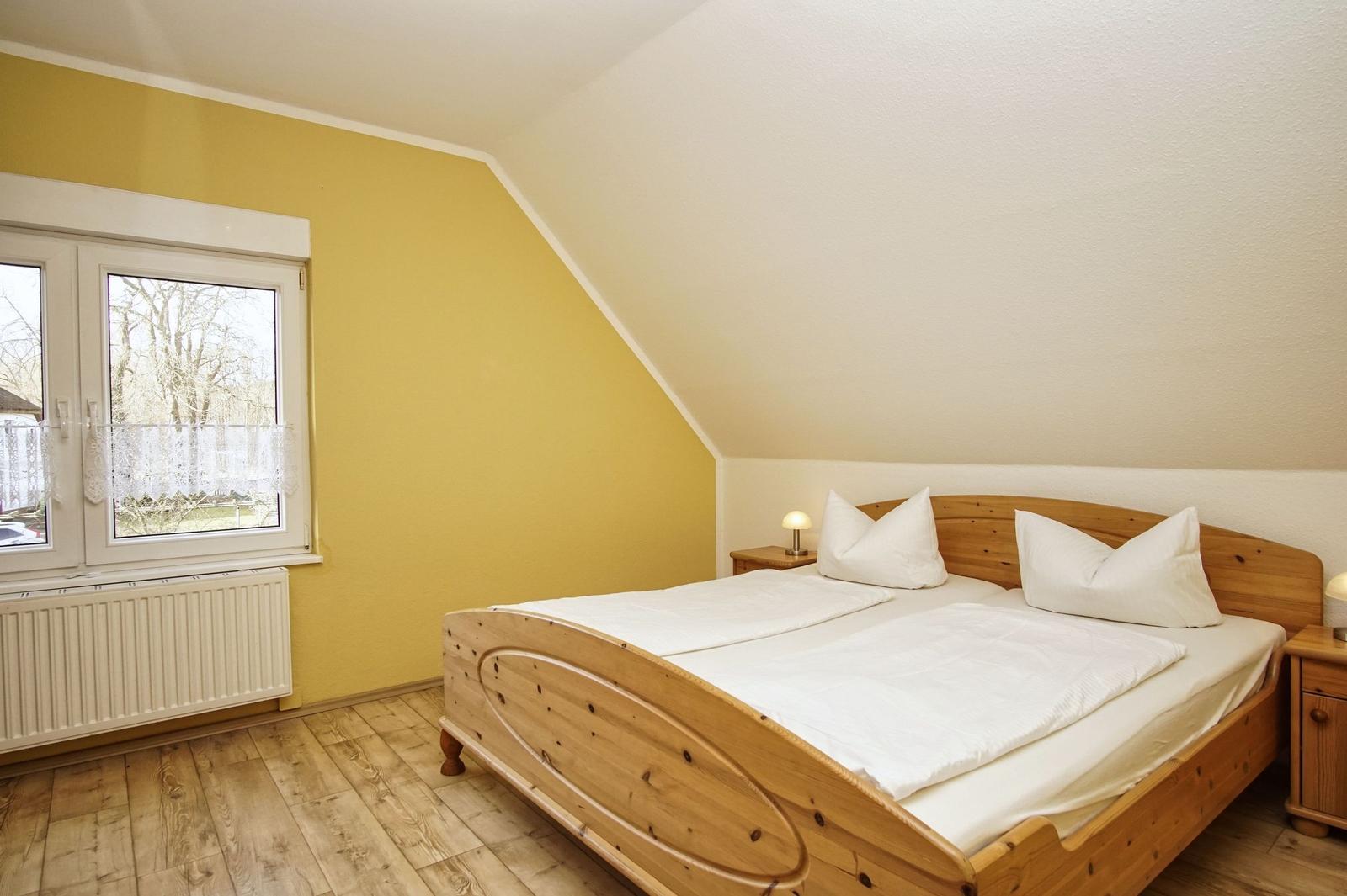 Schlafzimmer mit Holzbett, Fenster und Holzfußboden