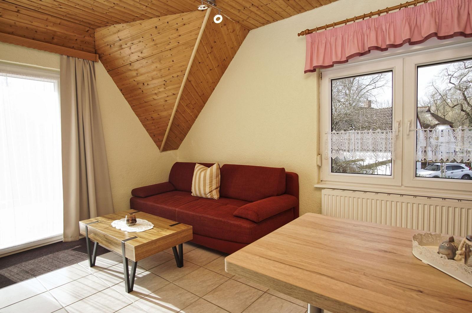 Ein Wohnzimmer mit rotem Sofa, Holztisch und Holzdach.